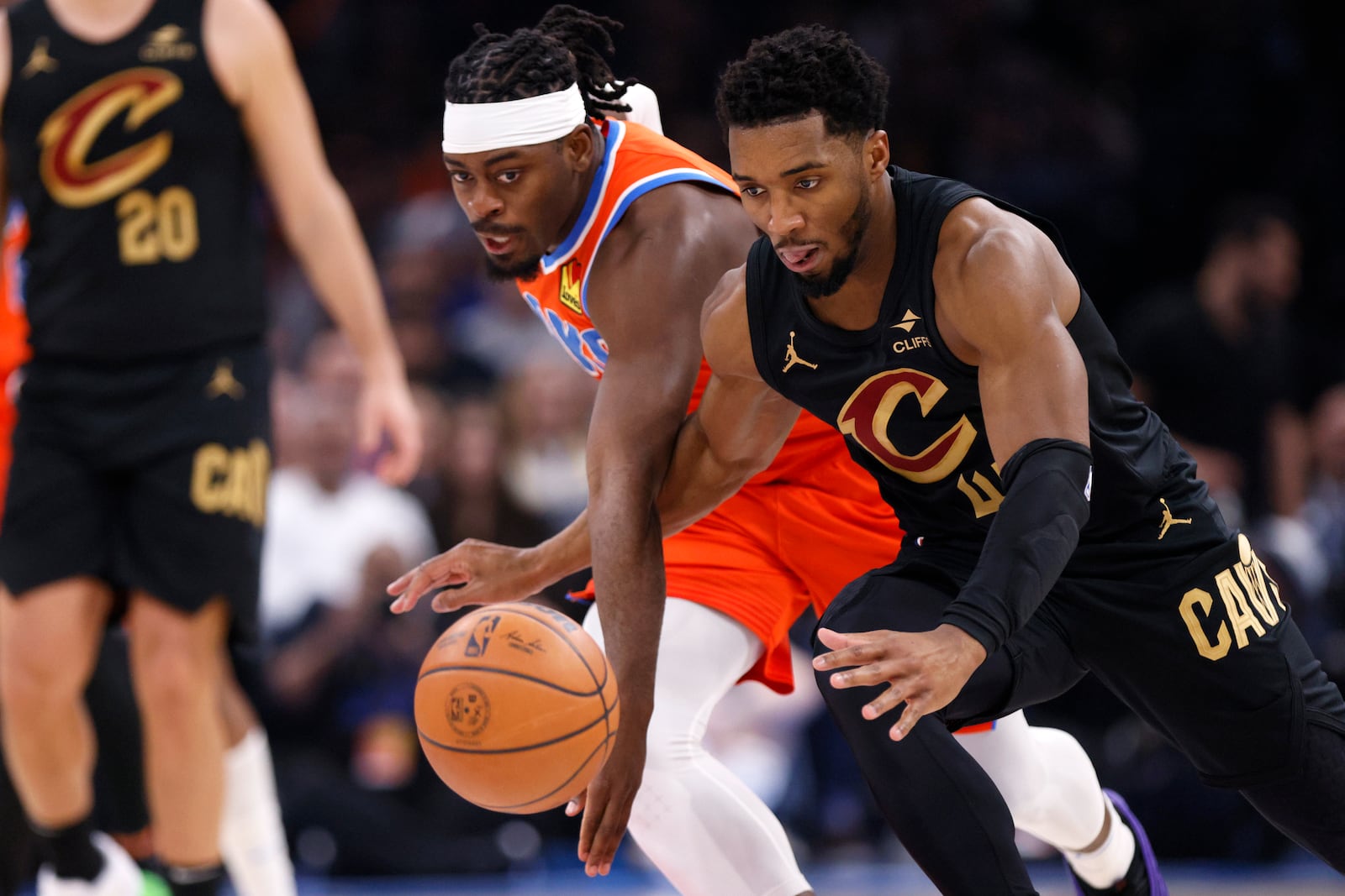 Oklahoma City Thunder guard Luguentz Dort, left, and Cleveland Cavaliers guard Donovan Mitchell, right, chase the ball during the first half of an NBA basketball game Thursday, Jan. 16, 2025, in Oklahoma City. (AP Photo/Nate Billings)