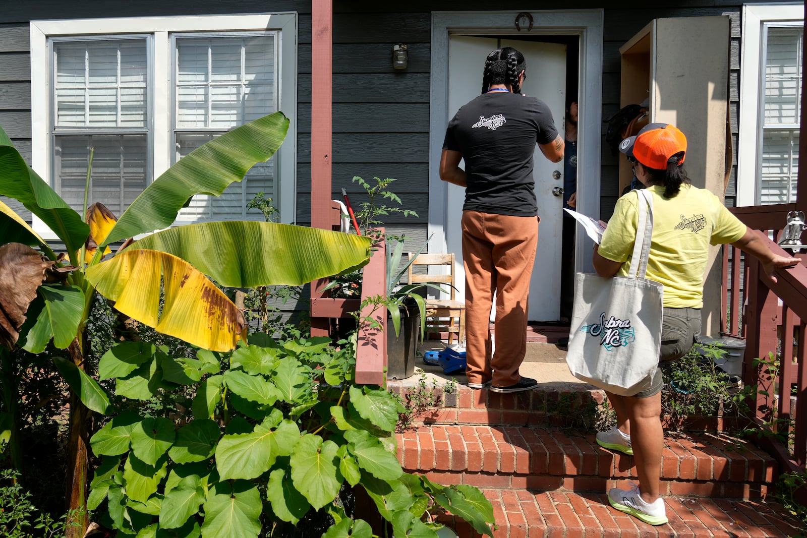 Salvador Fonseca, left, and Elena Jimenez talk to a homeowner during a voter engagement event for the Latino community in Greensboro, N.C., Saturday, Sept. 21, 2024. (AP Photo/Chuck Burton)