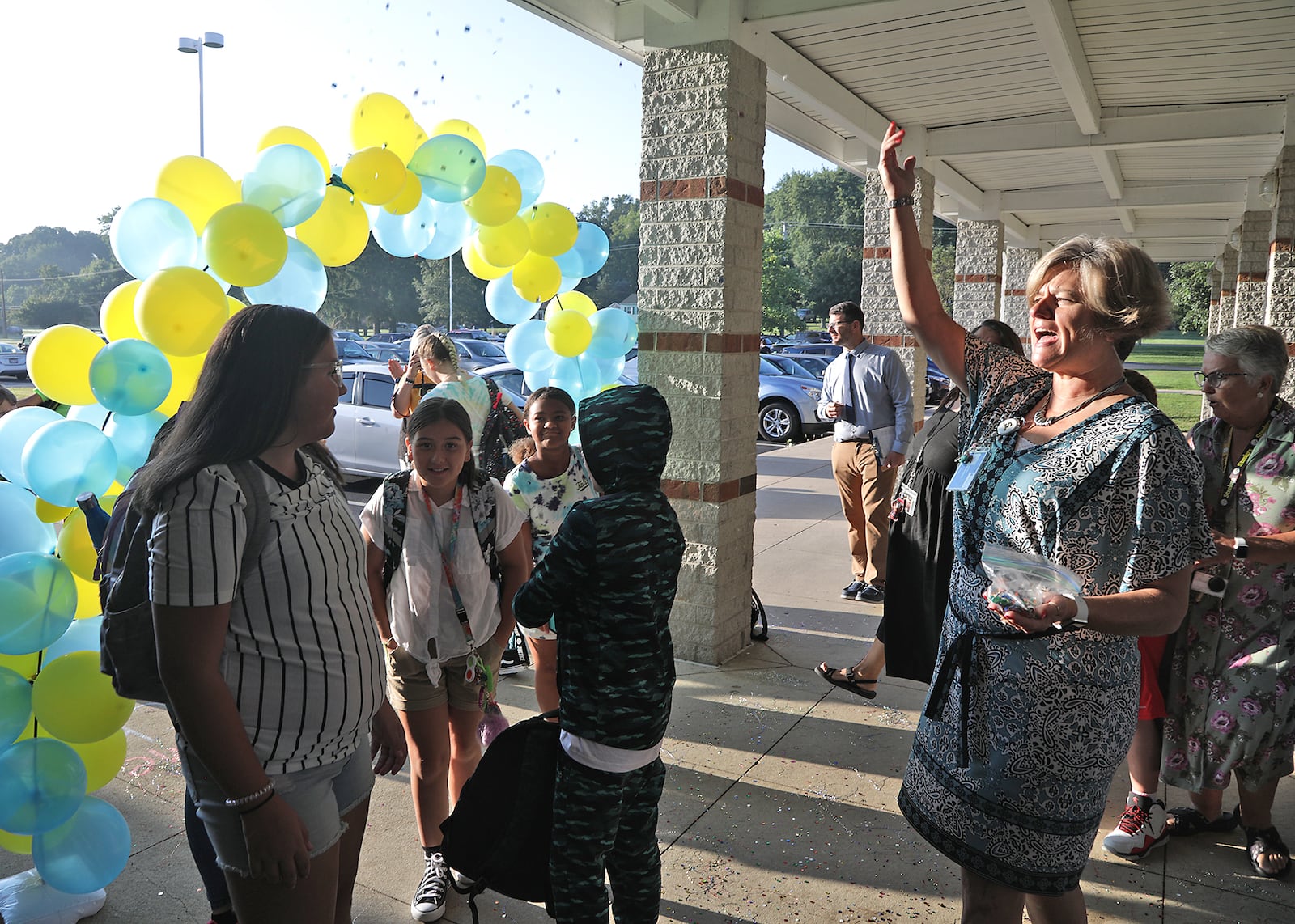 Jennifer Ullery-Smith, principal at Warder Park-Wayne Elementary School, tosses glitter on returning students on the first day of school Wednesday, August 24, 2022. Smith tried to make the return to school special. As students arrived she would cheer and toss glitter and tensel on them. BILL LACKEY/STAFF