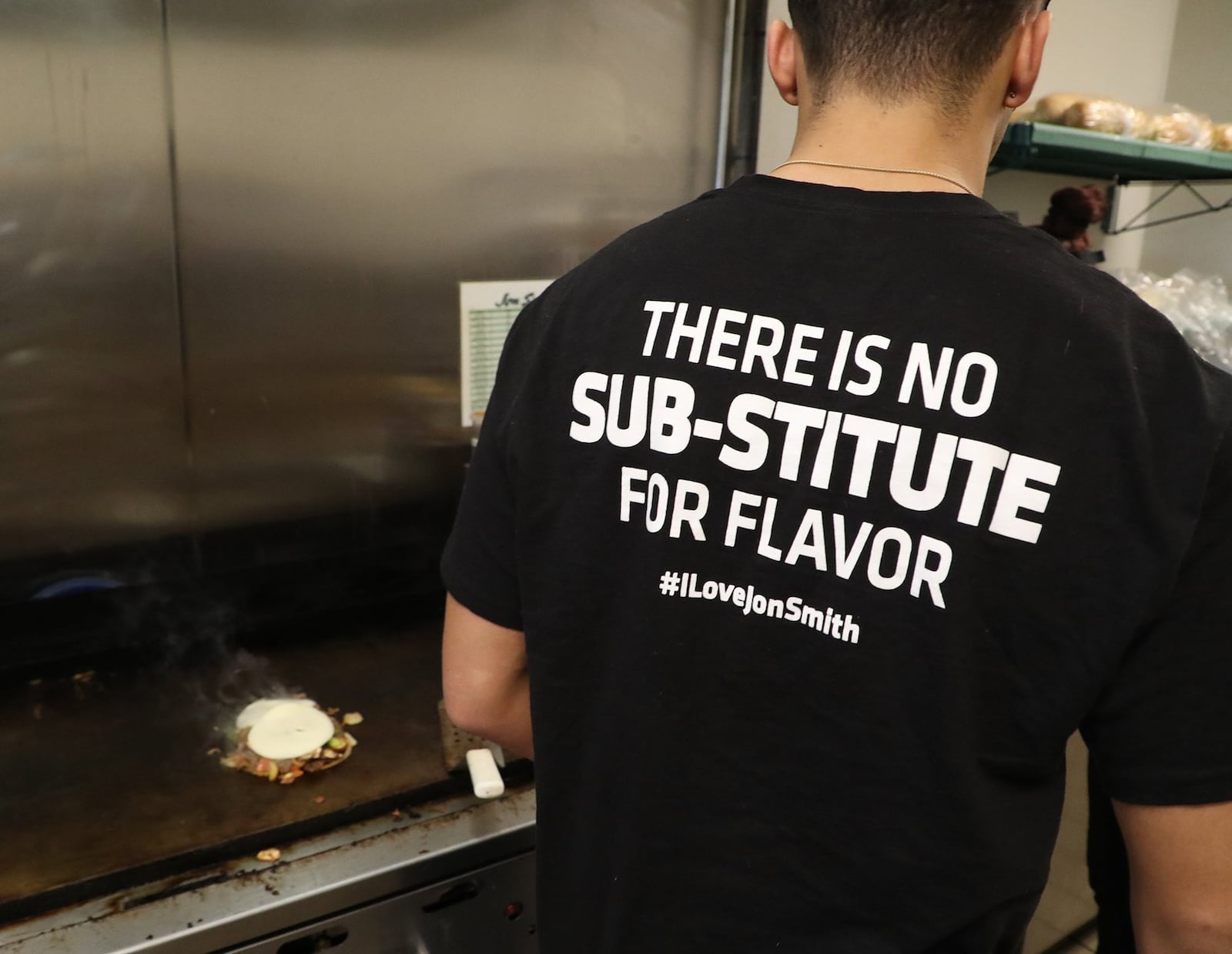 The back of a cook’s shirt says it all at Jon Smith Subs. BILL LACKEY/STAFF