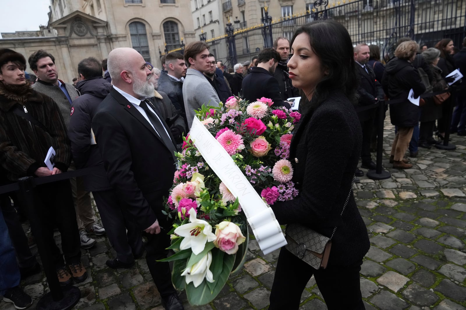 A woman bring a wreath a flowers at Notre Dame du Val-de-Grace church before a public memorial for late far-right leader Jean-Marie Le Pen, Thursday, Jan. 16, 2025 in Paris. Jean-Marie Le Pen, the founder of France's main far-right party, died on Jan.7, 2025 aged 96. (AP Photo/Michel Euler)