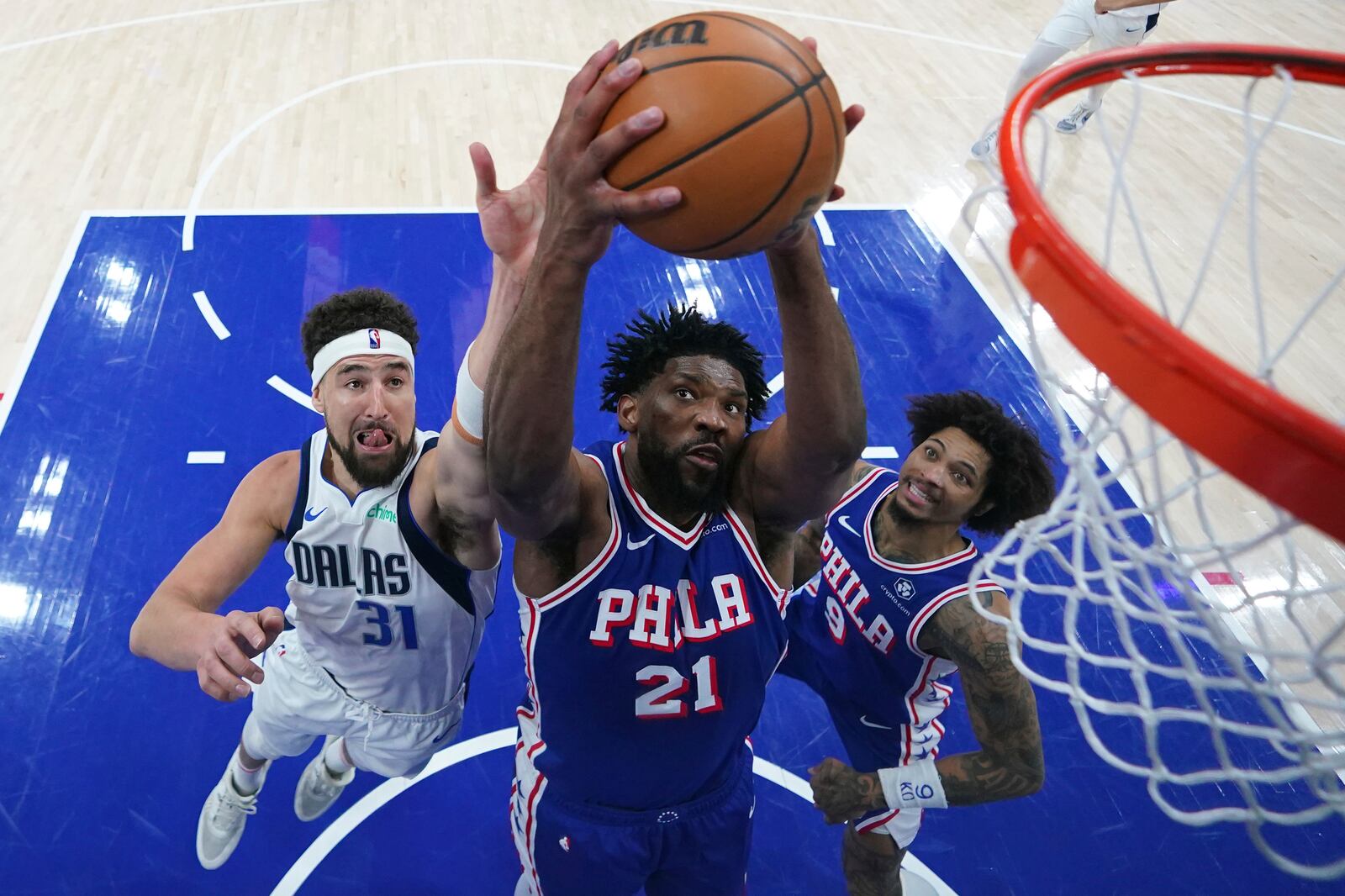 Philadelphia 76ers' Joel Embiid, center, pulls in a rebound between Dallas Mavericks' Klay Thompson, left, and Kelly Oubre Jr. during the second half of an NBA basketball game, Tuesday, Feb. 4, 2025, in Philadelphia. (AP Photo/Matt Slocum)