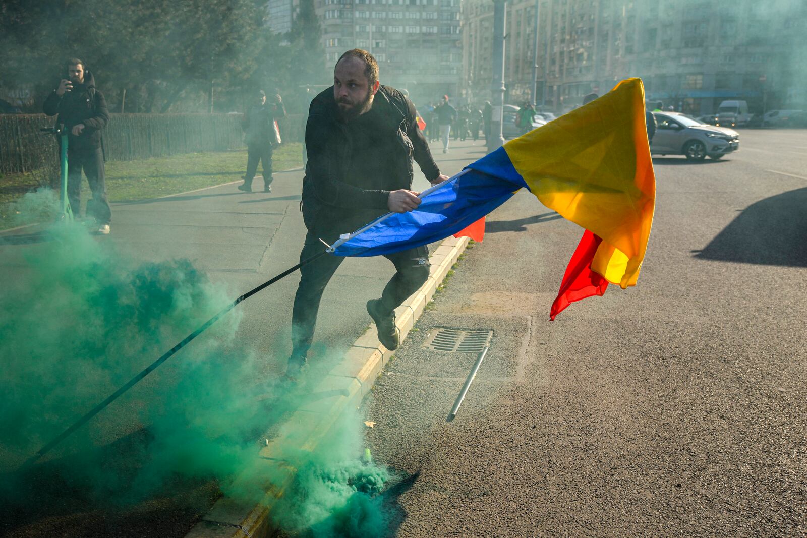 A man holding a Romanian flag runs after breaking through police lines in front of the government headquarters during a protest by supporters of Calin Georgescu, the winner of Romania's first round of presidential election which the Constitutional Court later annulled, in Bucharest, Romania, Monday, Feb. 10, 2025. (AP Photo/Vadim Ghirda)