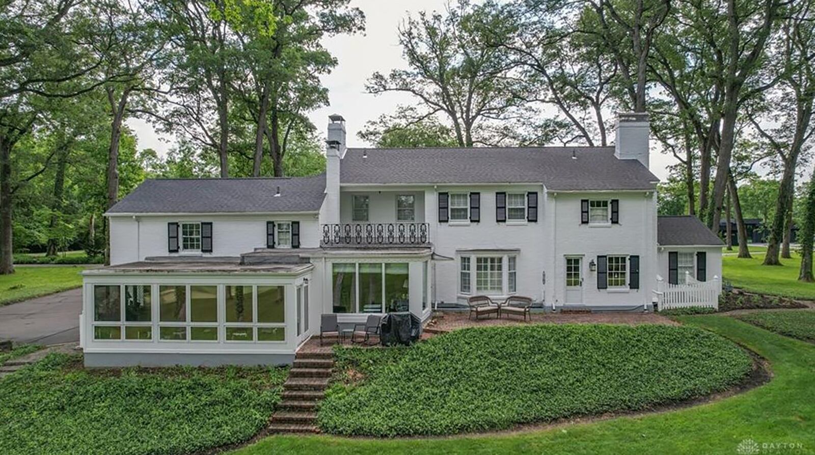 The rear of the home has a sunroom and family room addition, a paver patio and steps leading down to the backyard, which overlooks the golf course.