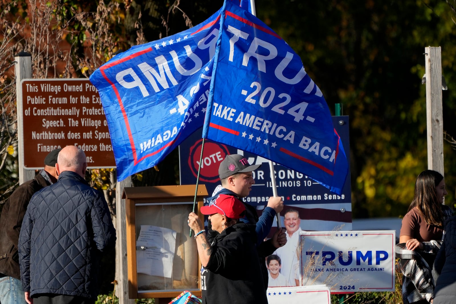 Supporters for Republican presidential nominee former President Donald J. Trump, hold up flags during a Trump rally in Northbrook, Ill., Sunday, Oct. 27, 2024. (AP Photo/Nam Y. Huh)