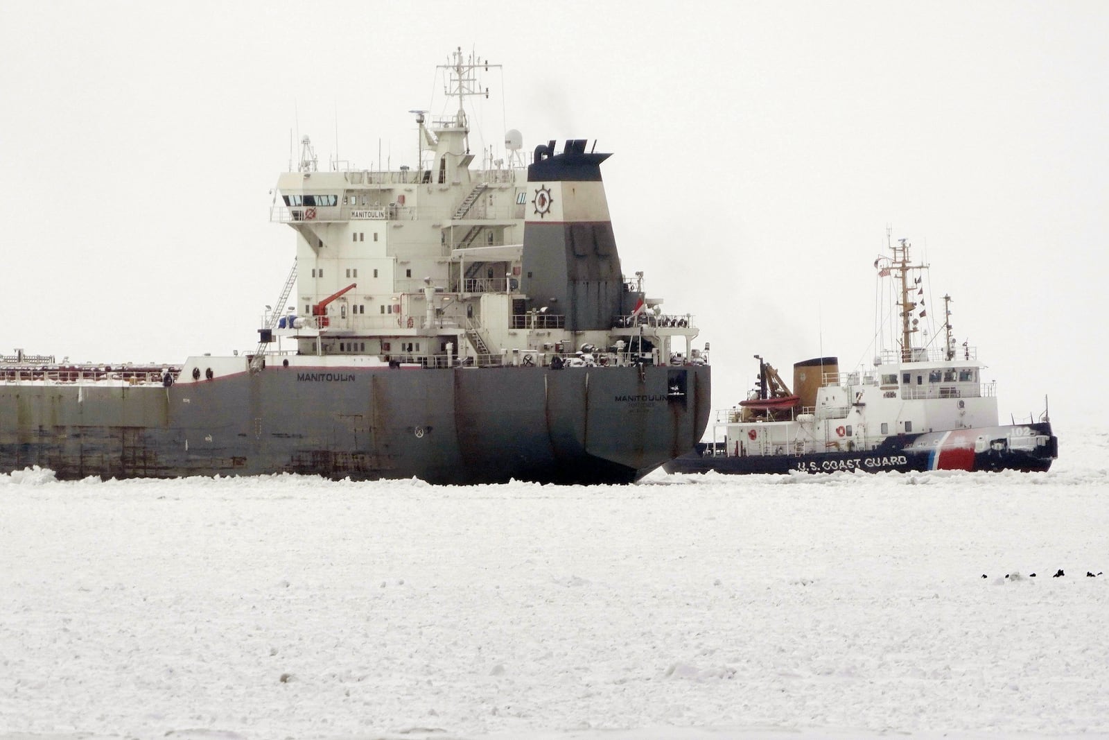 The U.S. Coast Guard Cutter Bristol Bay, right, breaks ice, Friday, Jan. 24, 2025, on Lake Erie around the lake freighter Manitoulin, which has been immobilized by thick lake ice since departing Buffalo on Wednesday morning, Jan. 22. (Derek Gee/The Buffalo News via AP)