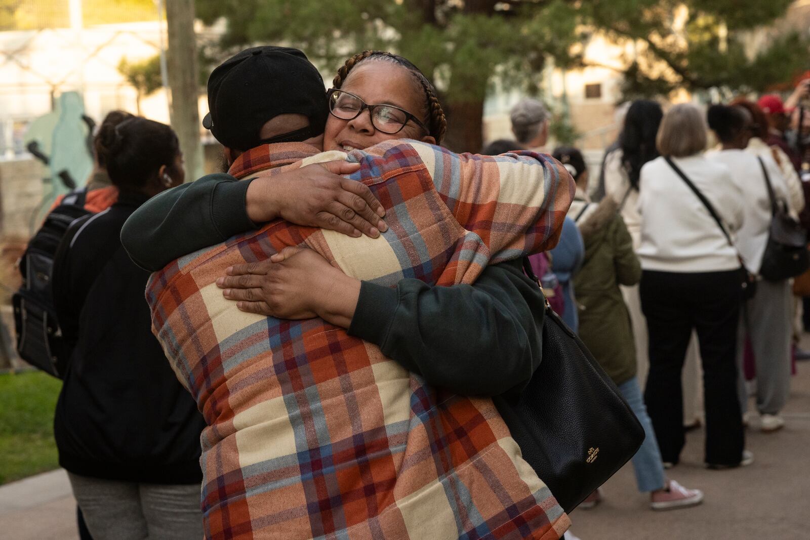 People impacted by the Eaton Fire take each other in their arms as they wait in line to access Pasadena City College's gymnasium where The Change Reaction will be handing out about 1,000 checks of between $2,500-$5,000, Tuesday, Jan. 28, 2025 in Pasadena, Calif. (AP Photo/Etienne Laurent)