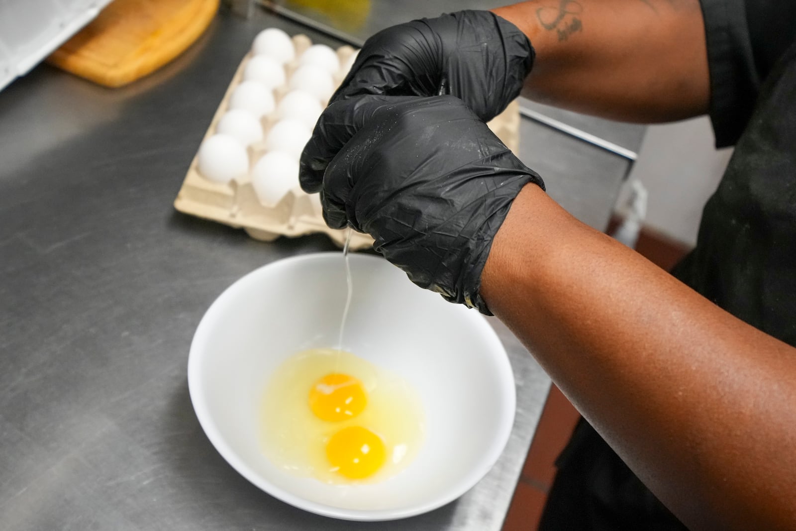 Johkiya Pierre cracks eggs while preparing a fresh omelette at The Breakfast Brothers restaurant, Wednesday, Feb. 12, 2025, in Arlington, Texas. (AP Photo/Julio Cortez)