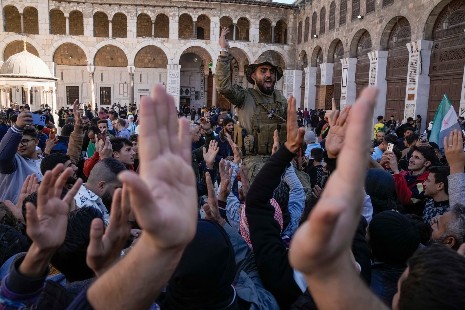 Syrians fighters and civilians chant slogans as they gather for Friday prayers at the Umayyad mosque in Damascus, Syria, Friday, Dec. 12, 2024. (AP Photo/Leo Correa)