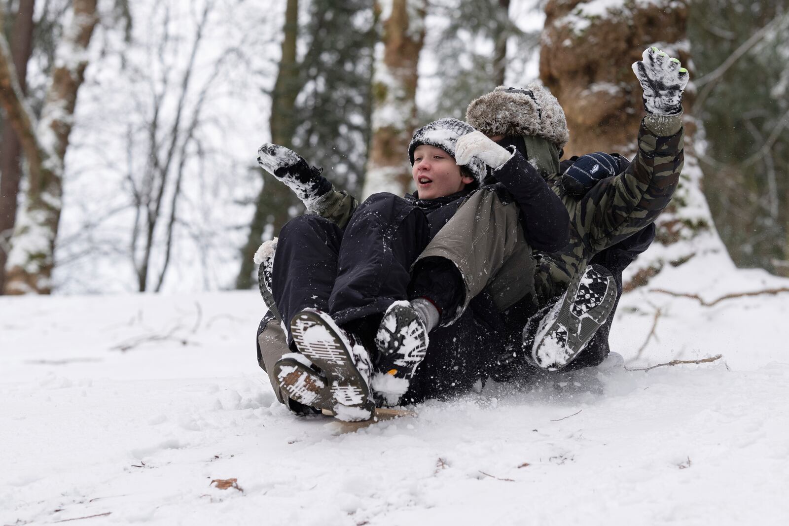 From left, Elijah, Jackson and Malian ride on a sled together down a hill at Laurelhurst Park on Thursday, Feb. 13, 2025, in Portland, Ore. (AP Photo/Jenny Kane)