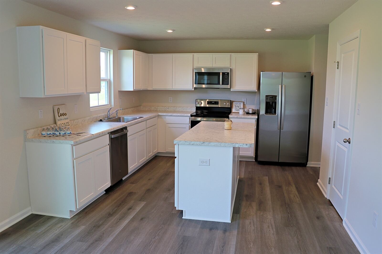 The spacious kitchen is fully equipped with stainless-steel appliances, including a range, microwave, dishwasher and refrigerator. A window is above the double sink and an island has an extended counter.