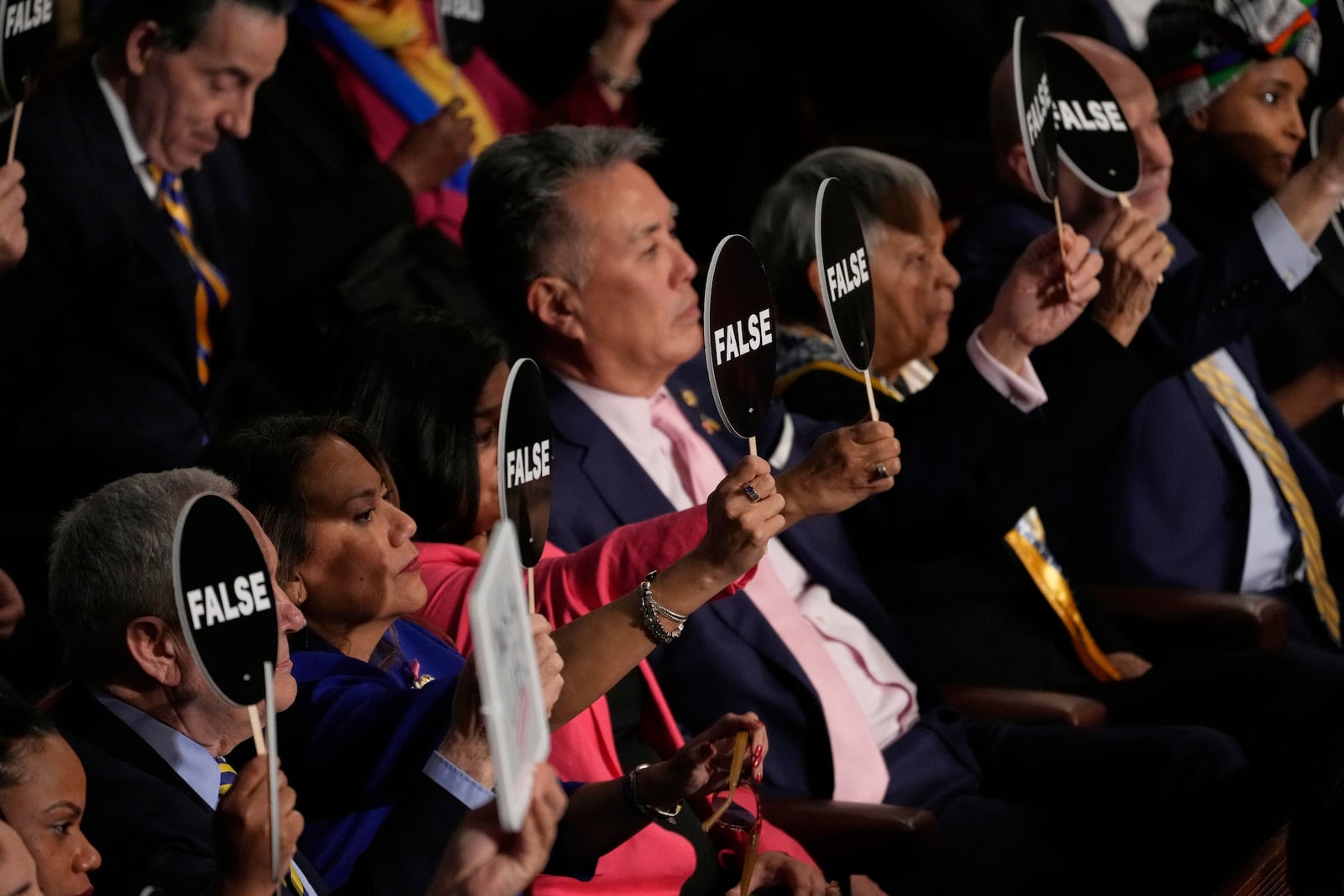 Democrats hold signs as President Donald Trump addresses a joint session of Congress in the House chamber at the U.S. Capitol in Washington, Tuesday, March 4, 2025. (AP Photo/Julia Demaree Nikhinson)