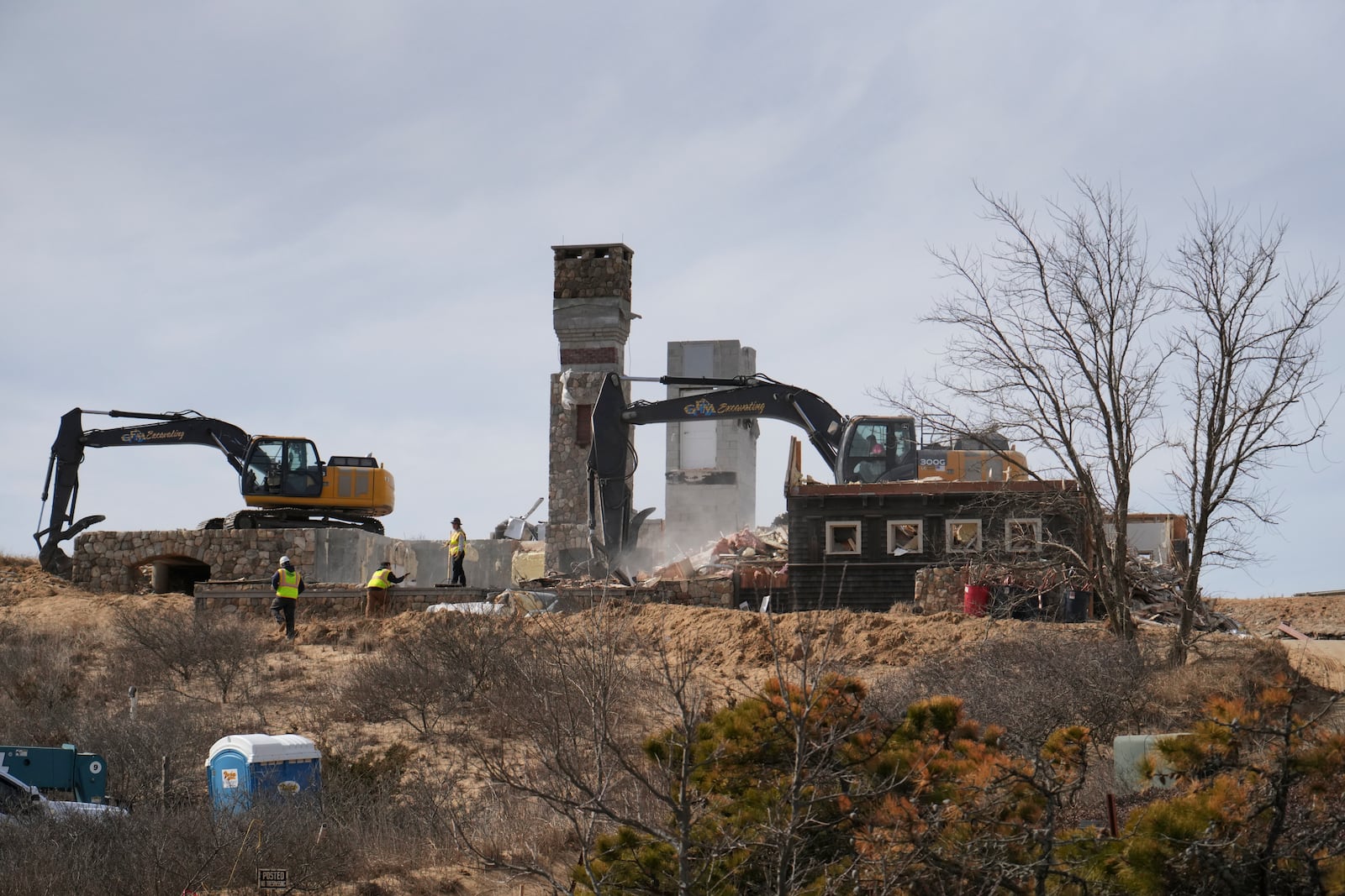 A home is demolished that sits atop of a sandy bluff overlooking a beach in Wellfleet, Mass., Tuesday, Feb. 25, 2025. (AP Photo/Andre Muggiati)