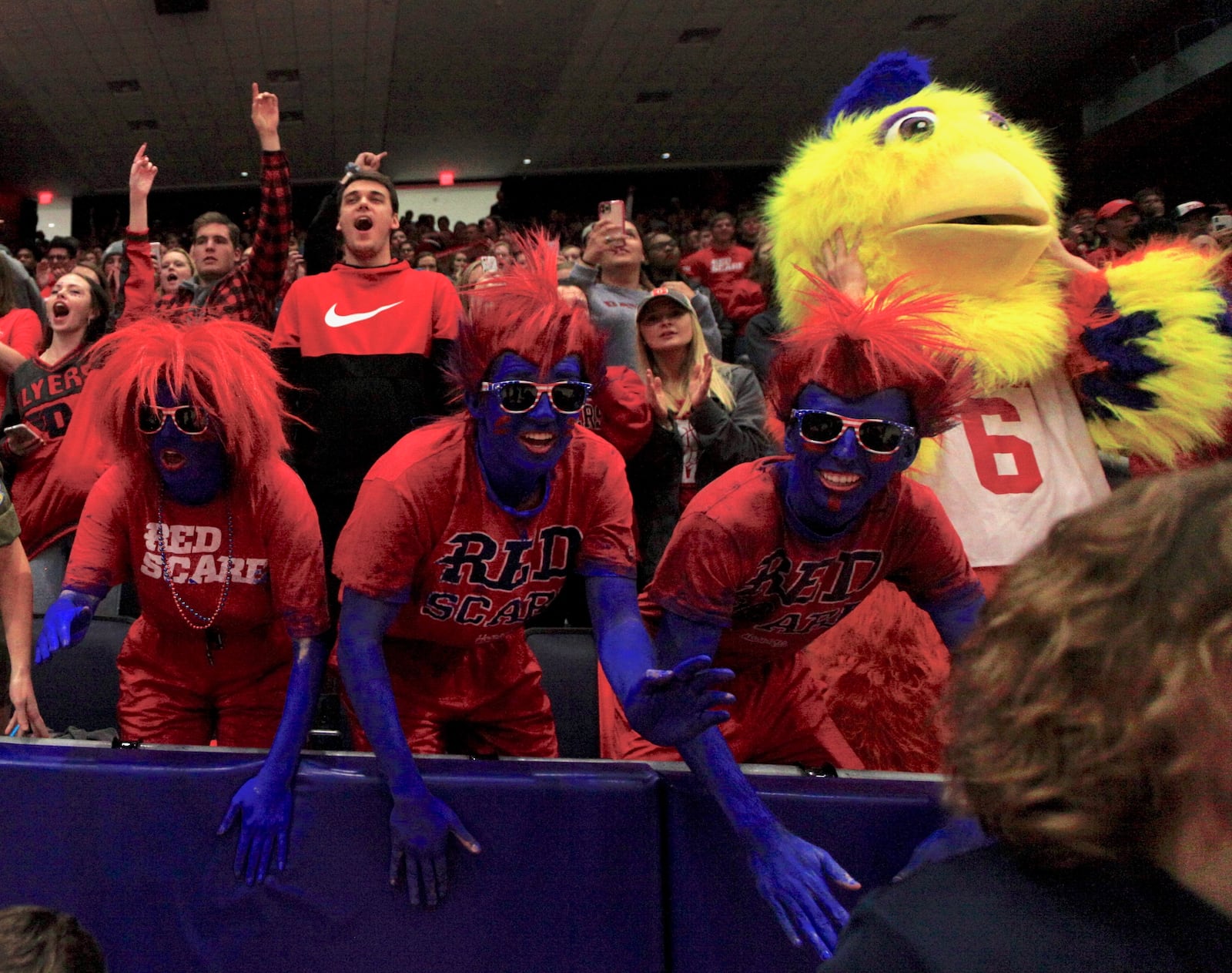 Katie Acra, Kyle Brun and Tommy Reese cheer in the Red Scare student section during a game in the 2019-20 season.