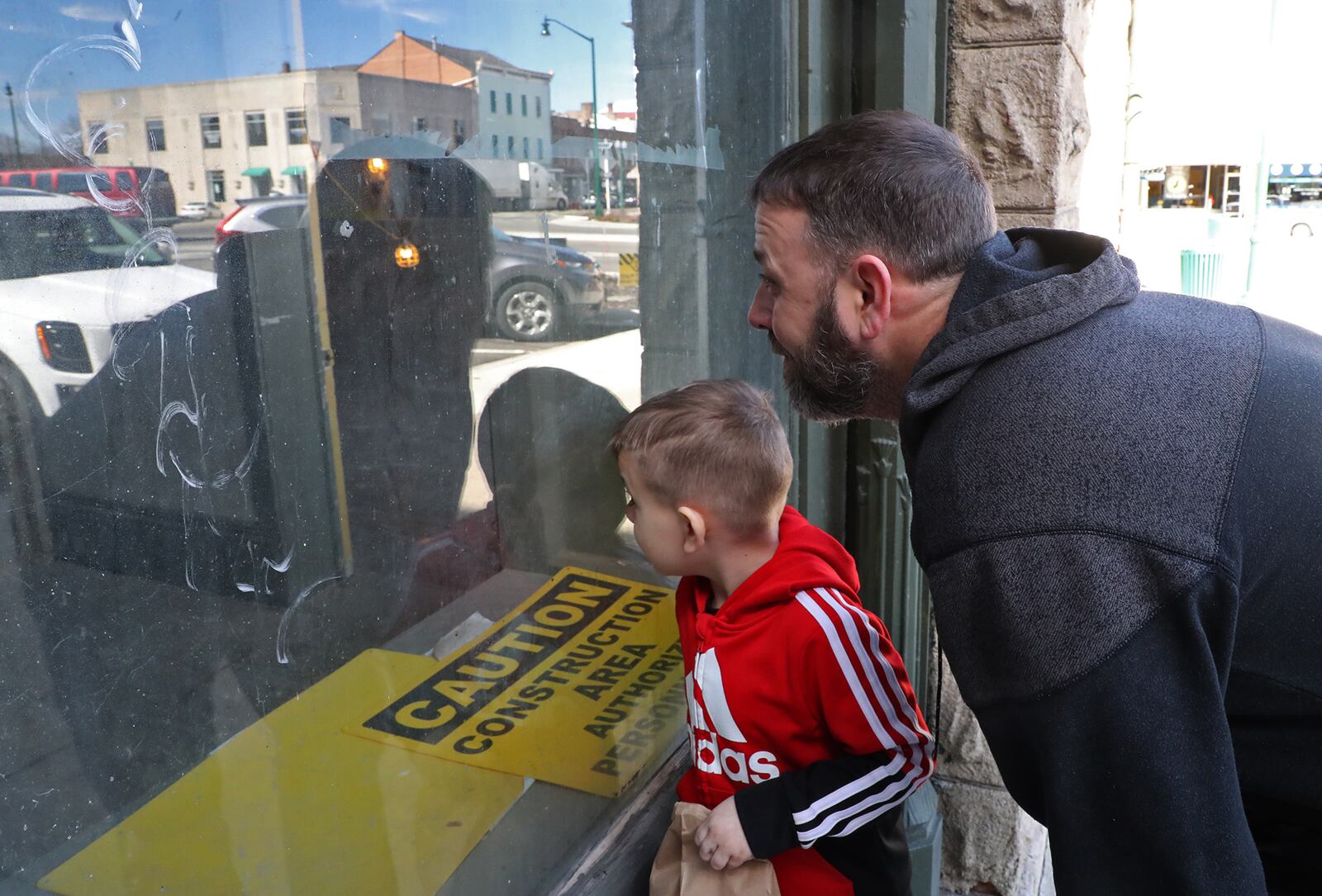 Trent Spriggs and his son, Tyrion, peak through one of the windows of the Douglas Hotel as they check out the renovations going on inside in March. BILL LACKEY/STAFF