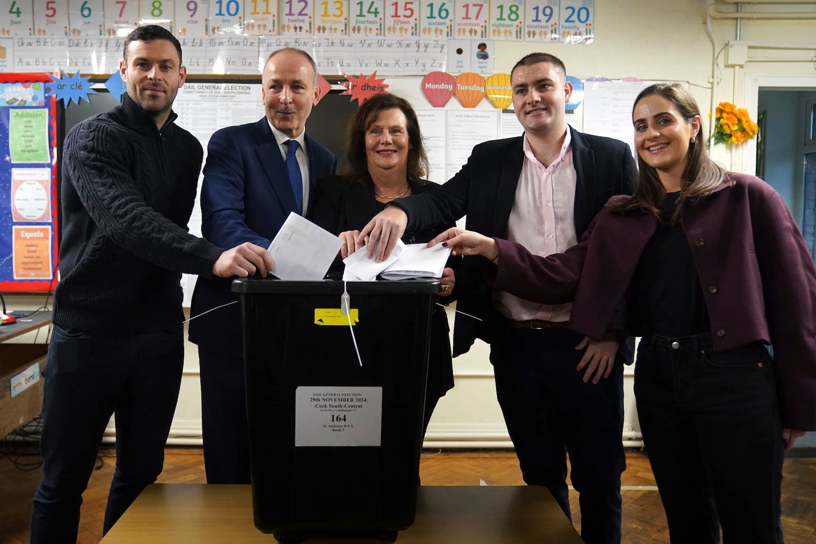 Minister for Foreign Affairs, and Minister for Defence and Fianna Fail leader Micheal Martin, second left, accompanied by his wife Mary O'Shea, third from right, and his sons Micheal Aodh Martin, left, Ruairi Martin, second from right, and daughter Leana Martin, arrives to casts his vote at St Anthony's Boys' School, Beechwood Park, Ballinlough, Cork, as voters go to the polls for the 2024 General Election in Ireland, Friday, Nov. 29, 2024. (Jacob King/PA via AP)