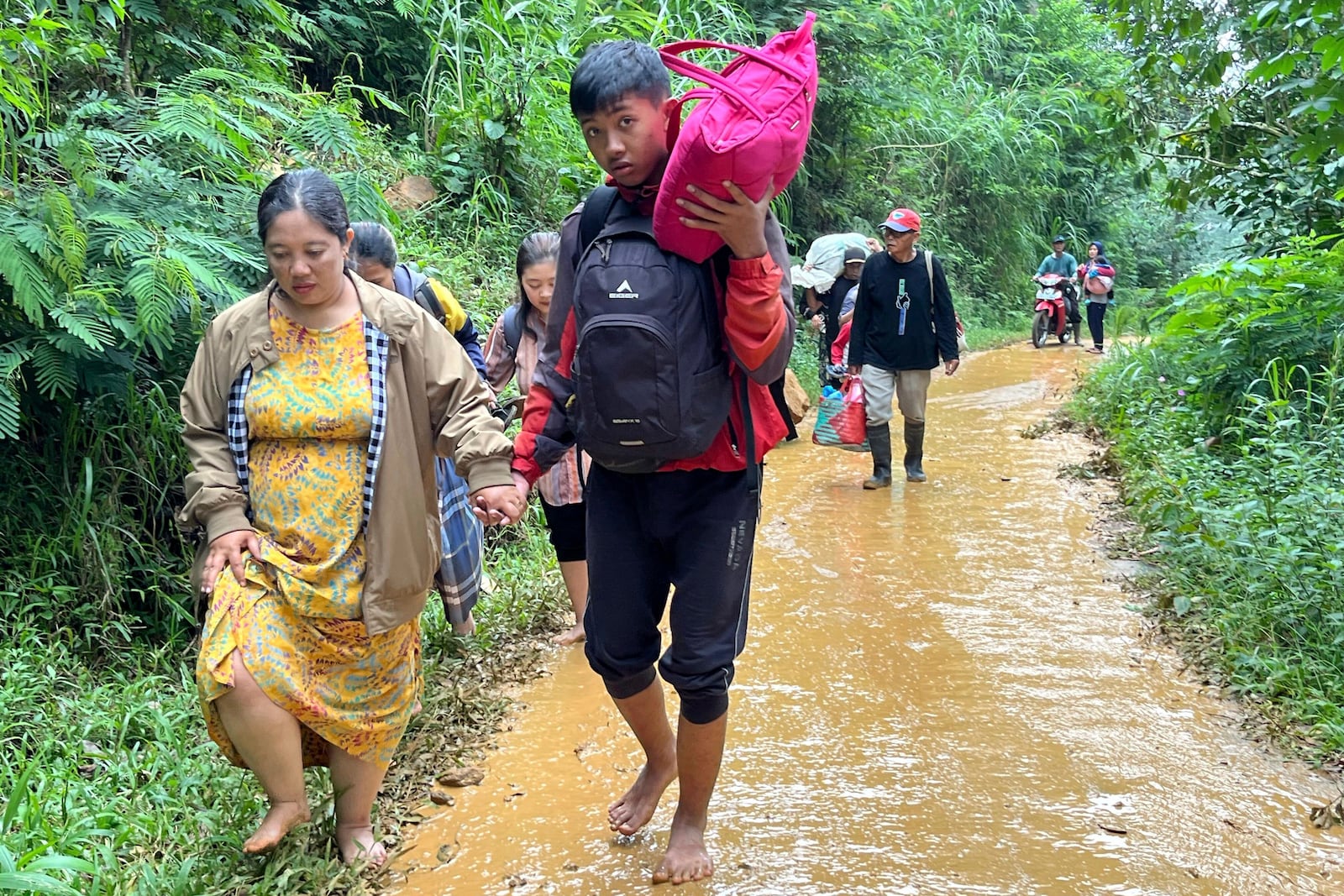 People affected by a flash flood walk on a muddy road in Pekalongan, Central Java, Indonesia, Wednesday, Jan. 22, 2025. (AP Photo/Janaki DM)