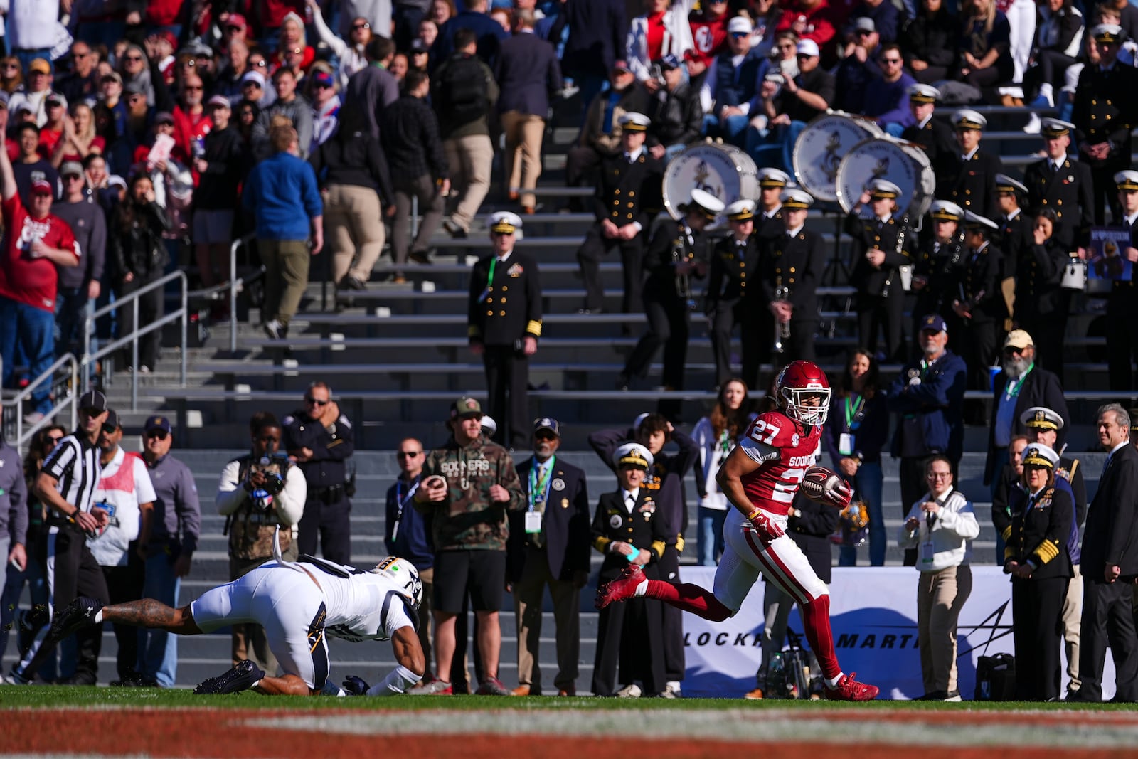 Oklahoma running back Gavin Sawchuk (27) laves behind Navy safety Rayuan Lane III on his way to a touchdown during the first half of the Armed Forces Bowl NCAA college football game, Friday, Dec. 27, 2024, in Fort Worth, Texas. (AP Photo/Julio Cortez)