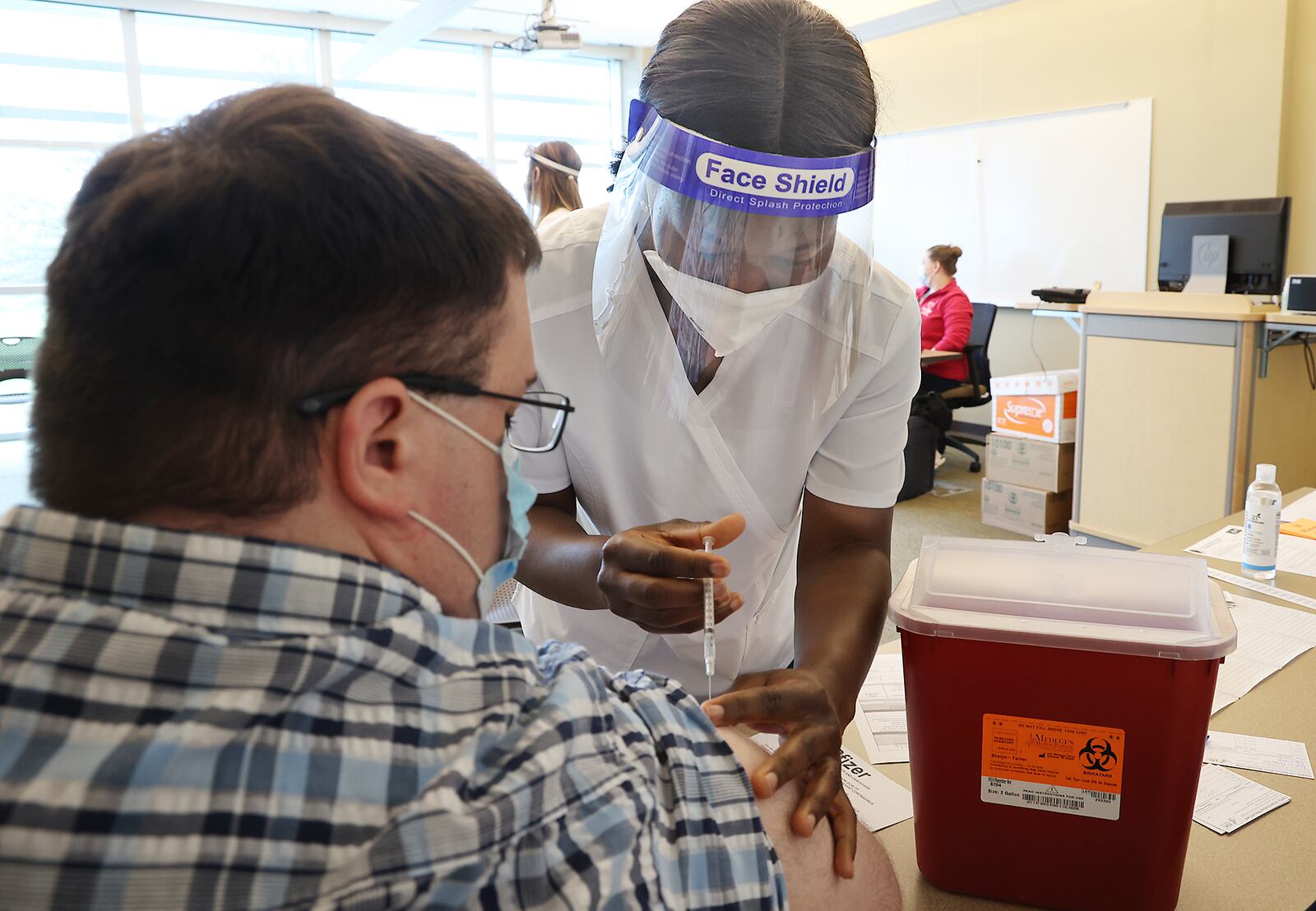 Vivian Adu, a nursing student at Clark State College, gives Andrew Deans a COVID-19 vaccine injection during a clinic at the college in April. Clark and Champaign counties are continue to host vaccine clinics as coronavirus cases tick up around the state. BILL LACKEY/STAFF