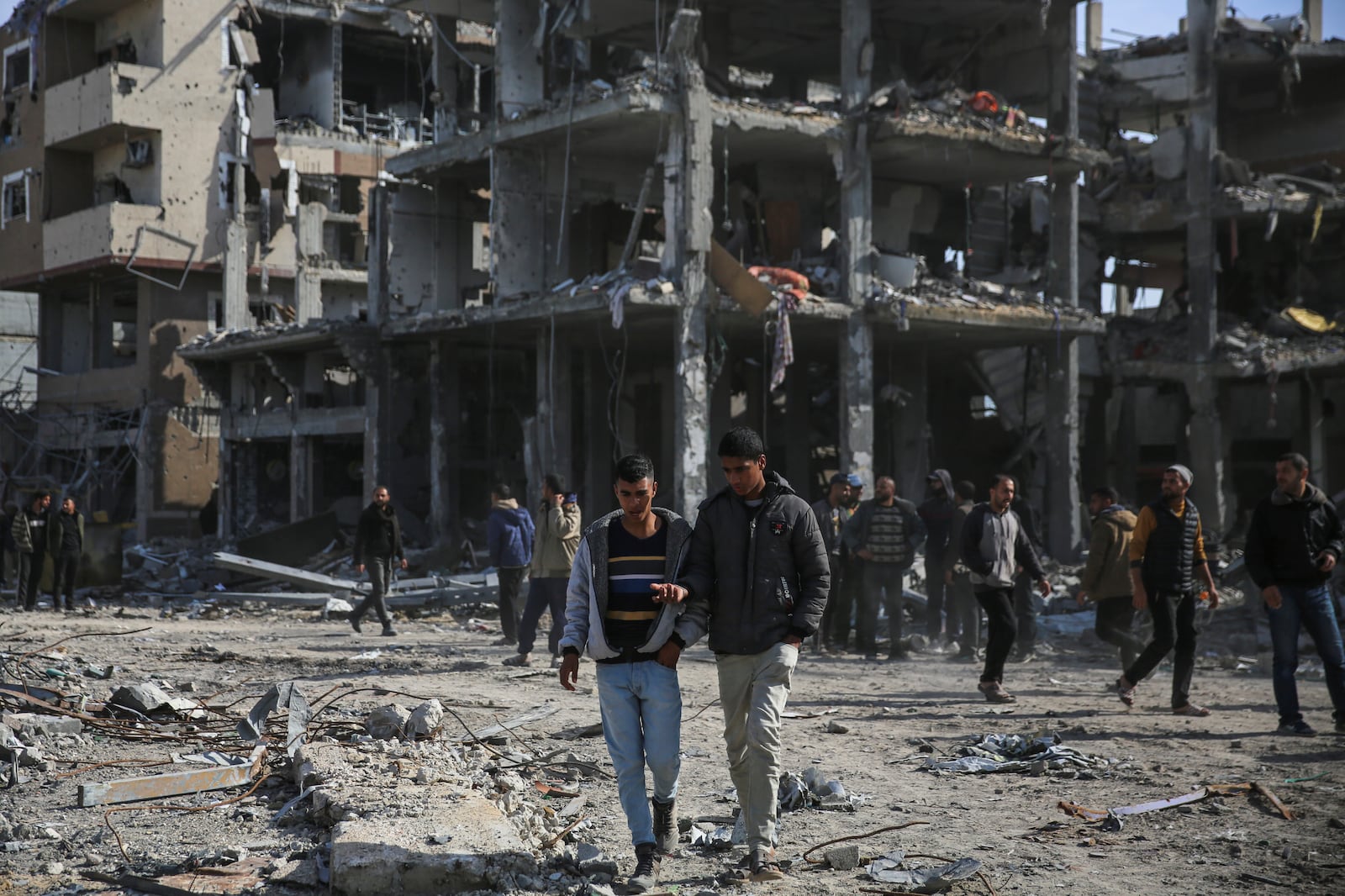 Palestinians walk amongst the destruction caused by the Israeli air and ground offensive, Sunday, Jan. 19, 2025, in Rafah, as a ceasefire deal between Israel and Hamas went into effect. (AP Photo/Mohammad Hajjar)