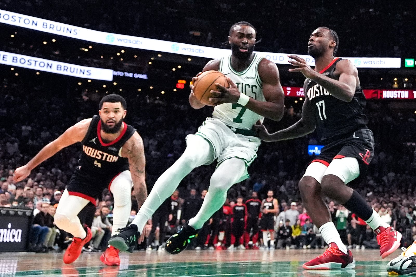 Boston Celtics guard Jaylen Brown (7) drives to the basket between Houston Rockets forward Tari Eason (17) and guard Fred VanVleet, left, during the second half of an NBA basketball game, Monday, Jan. 27, 2025, in Boston. (AP Photo/Charles Krupa)