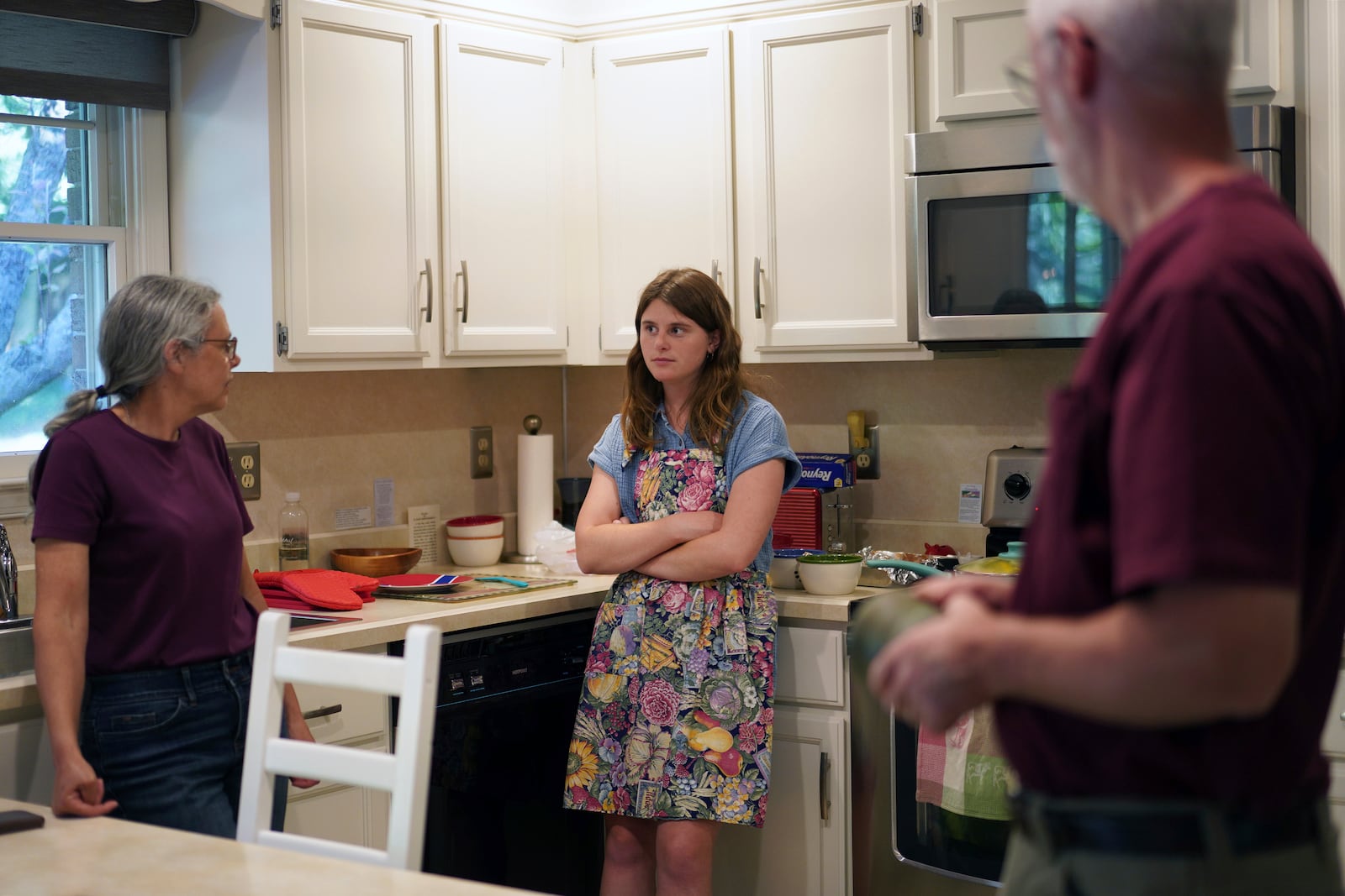 Zoey Stapleton, center, a current postulant at the Franciscan Sisters T.O.R., of Penance of the Sorrowful Mother, stands in the kitchen of her family home with parents, Peggy, right, and Tom, left, in Palmyra, Pa., Tuesday, July 2, 2024. (AP Photo/Jessie Wardarski)