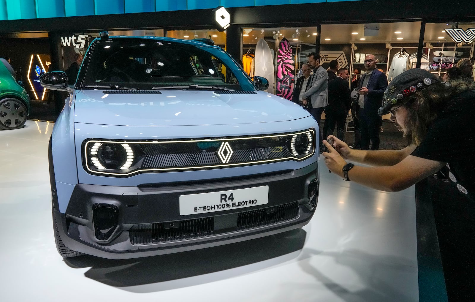 A man takes a photograph of a Renault R4 E-TECH car at the Paris Auto Show, in Paris, Monday, Oct. 14, 2024. (AP Photo/Michel Euler)