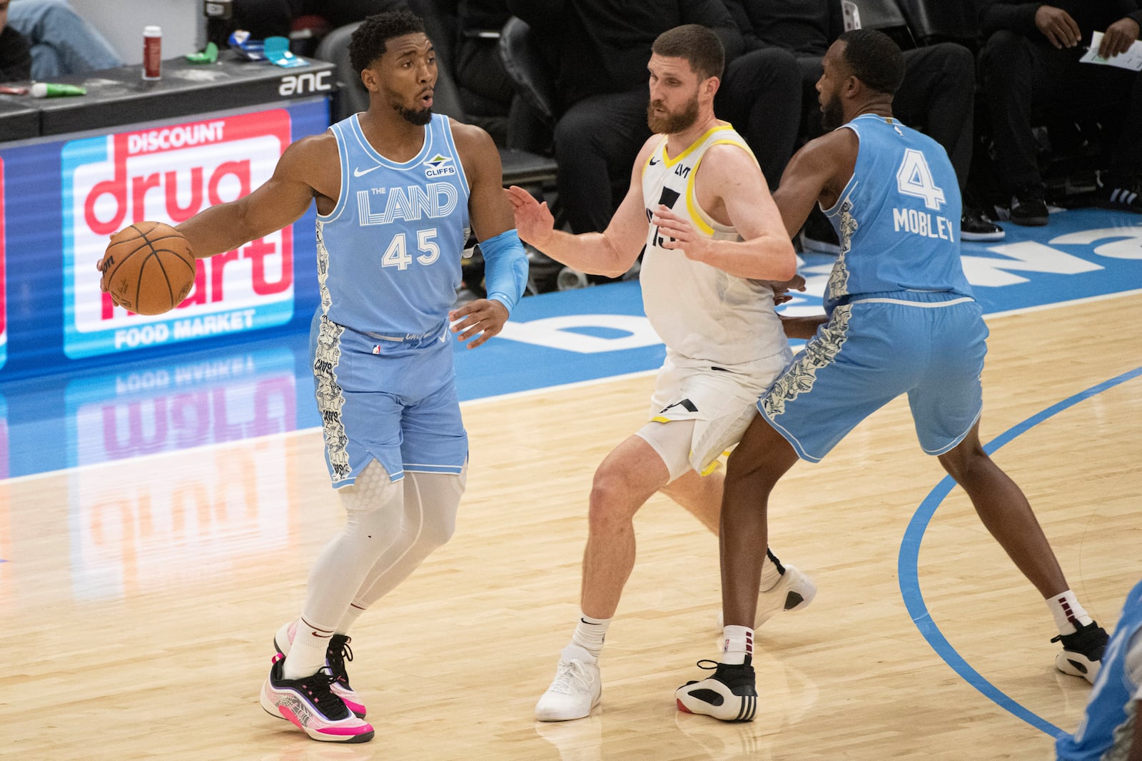 Cleveland Cavaliers' Donovan Mitchell (45) looks to pass as Utah Jazz Svi Myhailiuk, center, is blocked by Evan Mobley (4) during the first half of an NBA basketball game in Cleveland, Monday Dec. 23, 2024. (AP Photo/Phil Long)