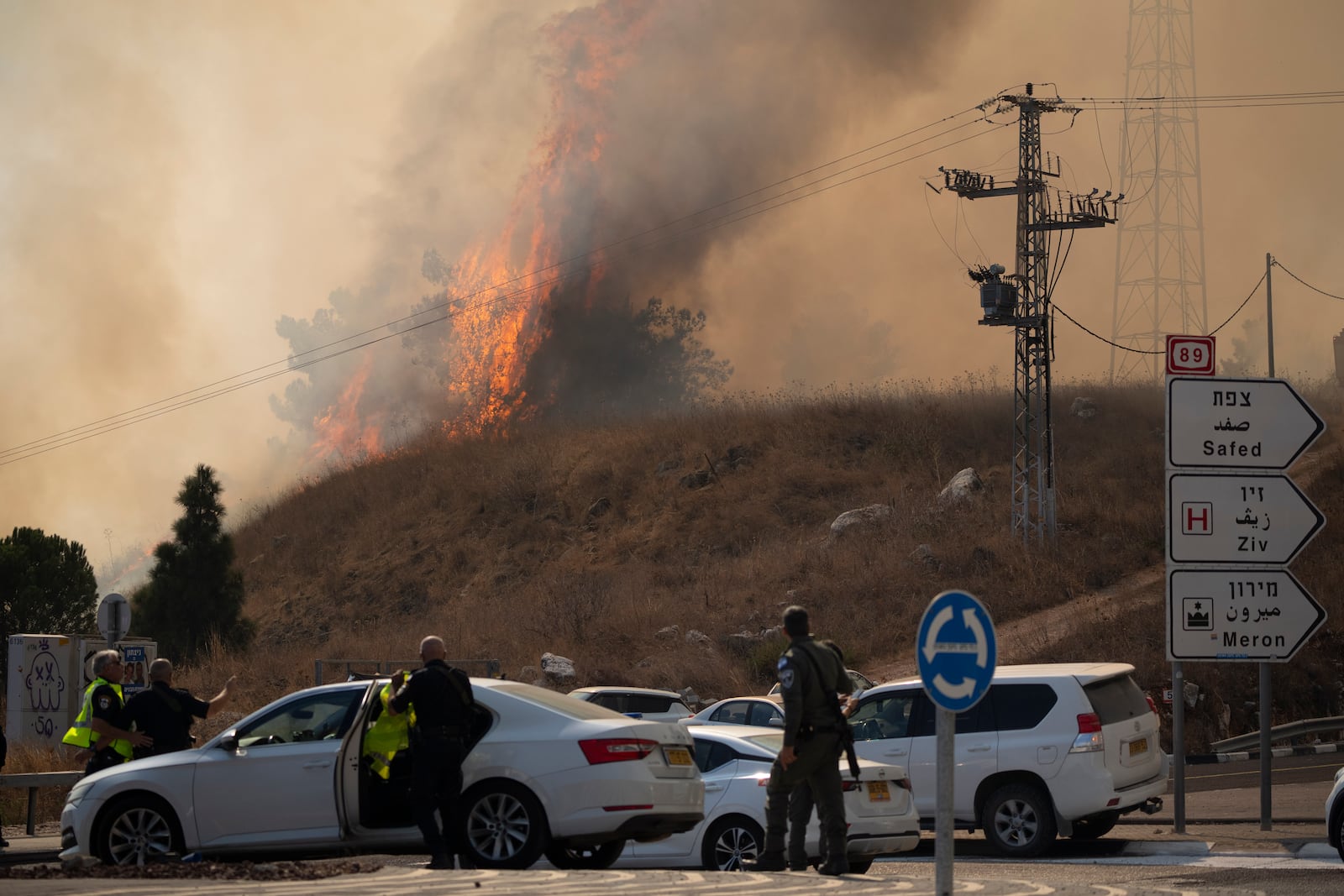 Members of the Israeli forces watch a fire after a rocket, fired from Lebanon, hit an area near the town of Rosh Pinna, northern Israel, Sunday, Oct. 20, 2024. (AP Photo/Leo Correa)