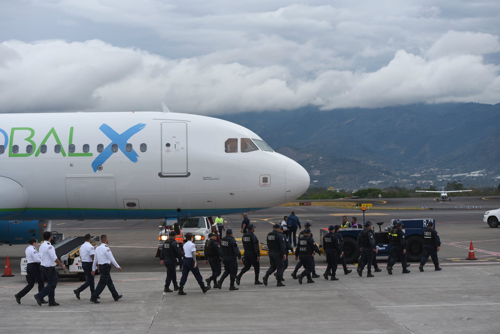 Security personnel approach a plane carrying migrants from Central Asia and India, deported from the United States, at Juan Santamaría International Airport in San Jose, Costa Rica, Thursday, Feb. 20, 2025. (AP Photo/Jose Diaz)