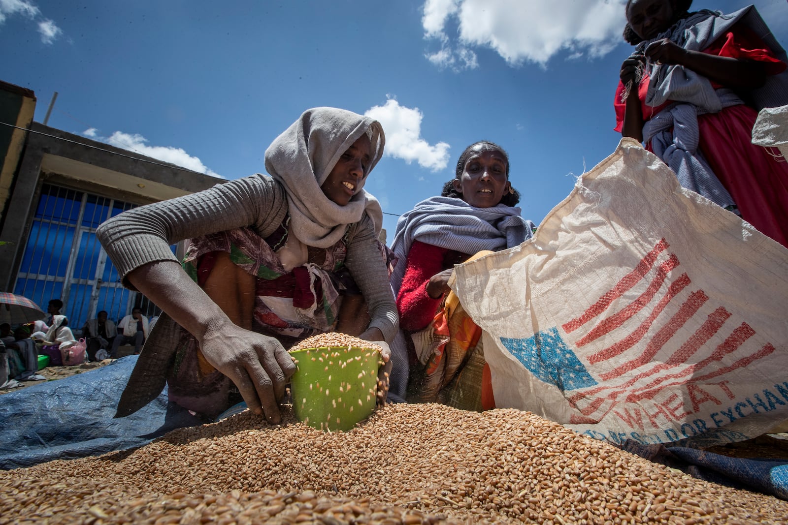 FILE-An Ethiopian woman scoops up portions of wheat to be allocated to each waiting family after it was distributed by the Relief Society of Tigray in the town of Agula, in the Tigray region of northern Ethiopia, on Saturday, May 8, 2021. (AP Photo/Ben Curtis, file)