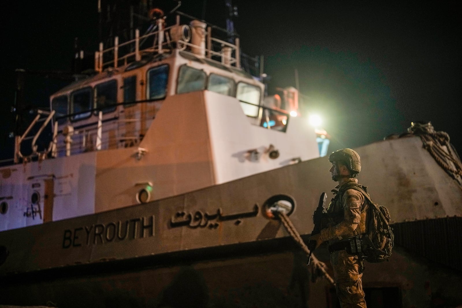 A Turkish security personnel stands guard next to Turkish military ships preparing to evacuate citizens from Lebanon to Turkey, in Beirut port, Wednesday, Oct. 9, 2024. (AP Photo/Emrah Gurel)