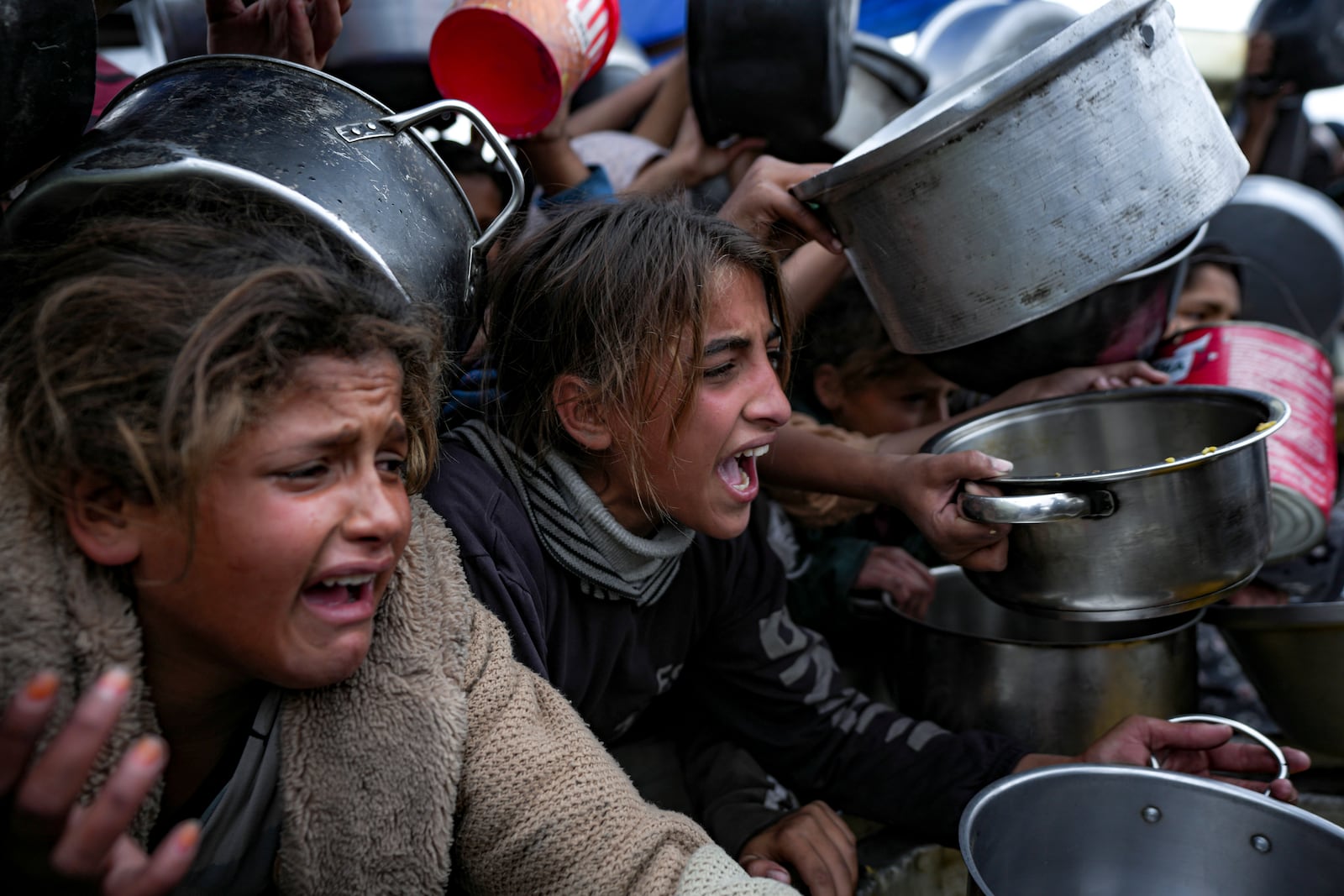 Palestinian girls struggle to reach for food at a distribution center in Khan Younis, Gaza Strip, Friday, Dec. 20, 2024. (AP Photo/Abdel Kareem Hana)