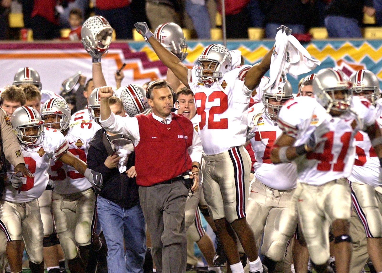 Ohio State coach Jim Tressel celebrates as he rushes the field with his players, including Roy Hall (82), at the end of the second overtime of the Fiesta Bowl in Tempe, Ariz., Friday, Jan. 3, 2003. Ohio State beat Miami 31-24. (AP Photo/Paul Sakuma)