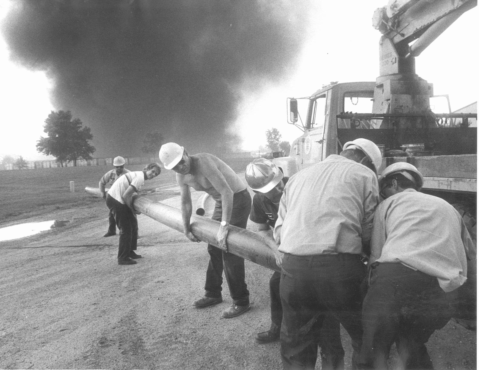 Sherwin-Williams warehouse fire 5/28/87 Dayton Water Supply workers put down rubber hose which will supply water to drain sewers. The sewers are on fire because of run off of from the Sherwin-Williams warehouse fire. A solvent which is water soluable is on fire in the sewers. Filling the sewers with water leaves no room for the fire to burn.