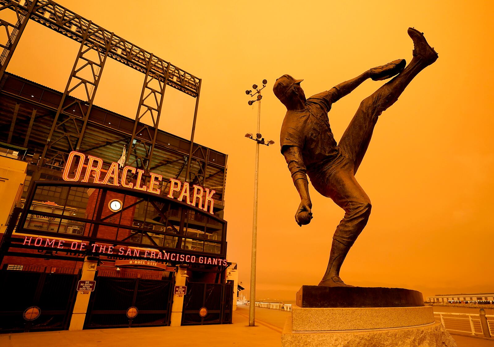 Wildfire smoke darkens the sky over a statue of former San Francisco Giants pitcher Juan Marichal outside Oracle Park before a baseball game between the Giants and the Seattle Mariners on Wednesday, Sept. 9, 2020, in San Francisco. People from San Francisco to Seattle woke Wednesday to hazy clouds of smoke lingering in the air, darkening the sky to an eerie orange glow that kept street lights illuminated into midday, all thanks to dozens of wildfires throughout the West. (AP Photo/Tony Avelar)