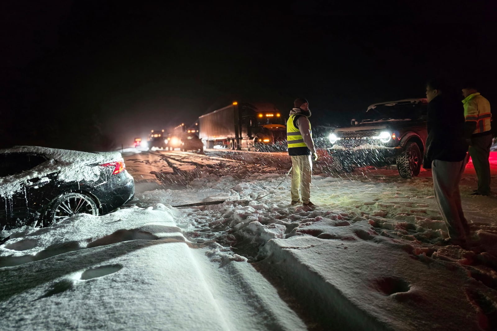 A car prepares to tow a stuck vehicle as cars sit in traffic backed up for more than 15 miles on a westbound stretch of Interstate 40 between Flagstaff and Williams, Ariz., Friday, March 7, 2025. (AP Photo/Felicia Fonseca)