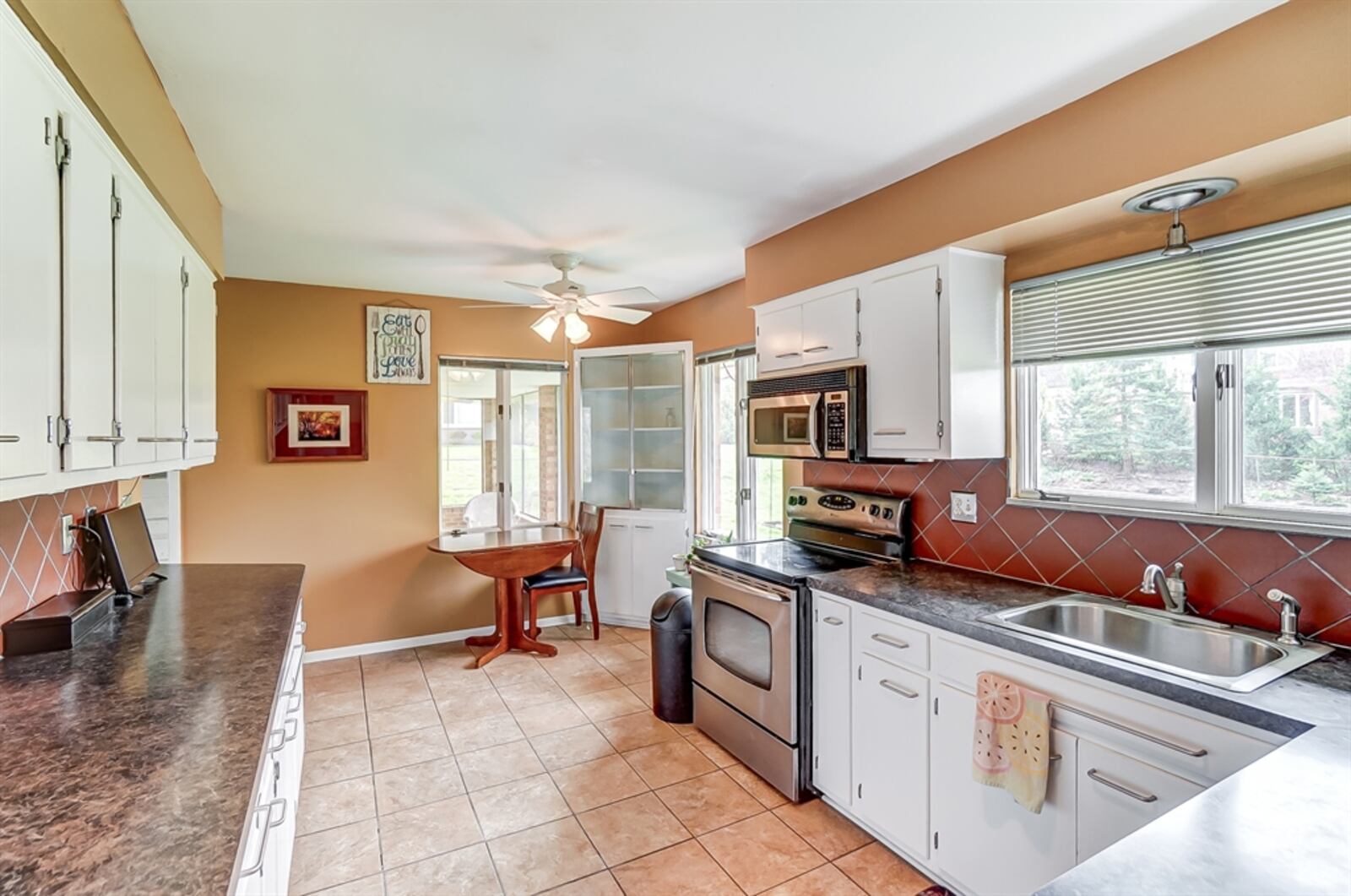 Off the dining room, the eat-in kitchen has white cabinetry with dark counters. 