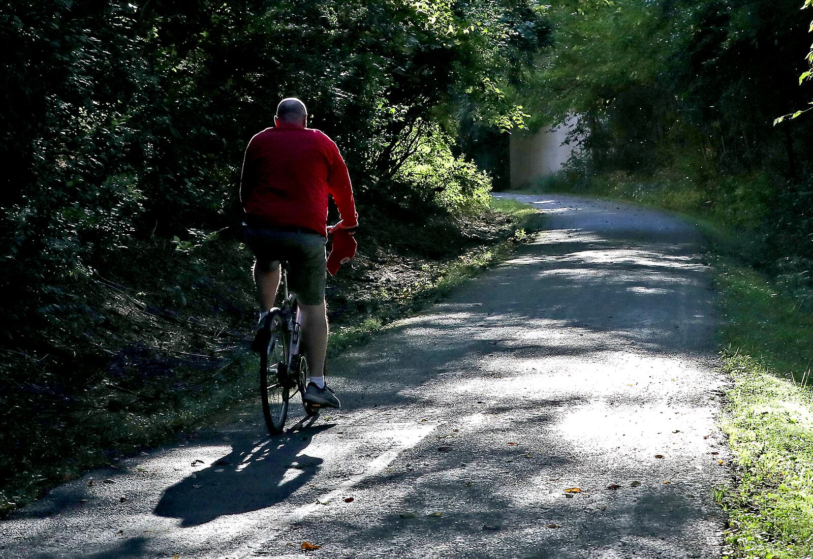 A bicyclist rides through the dappled sunlight as he makes his way along the Simon Kenton Trail in Springfield Tuesday, Oct. 5, 2022. BILL LACKEY/STAFF