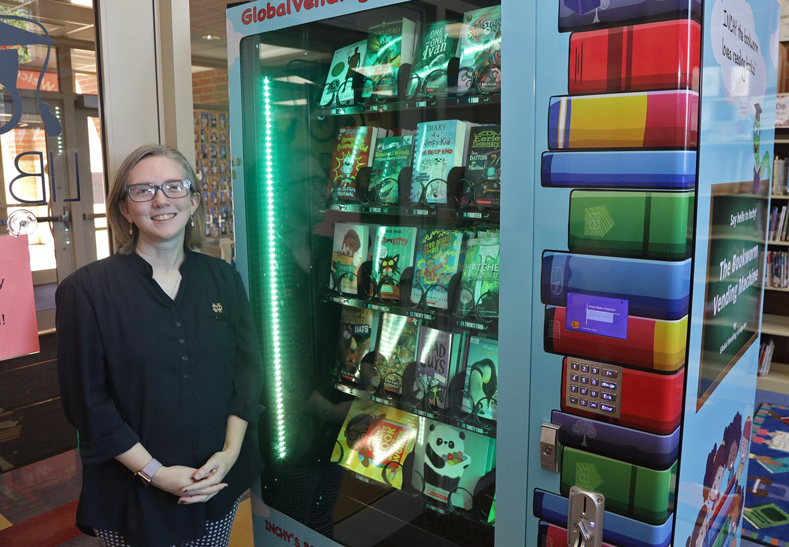 Greta Eber, Librarian at Donnelsville Elementary School, with the book vending machine. Students can earn tokens to use in the machine to purchase a book, which then dispenses it like a bag of chips. BILL LACKEY/STAFF