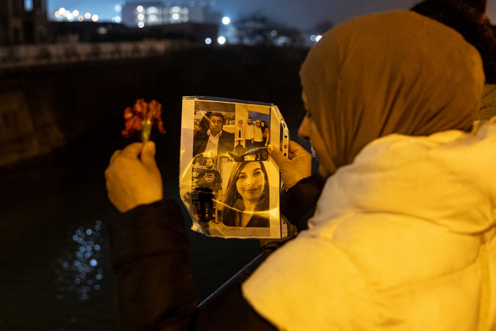 People toss carnations into the Orontes River as they mark the two-year anniversary of the country's catastrophic earthquake, in Antakya, southern Turkey, early Thursday, Feb. 6, 2025. (Ugur Yildirim/Dia Photo via AP)