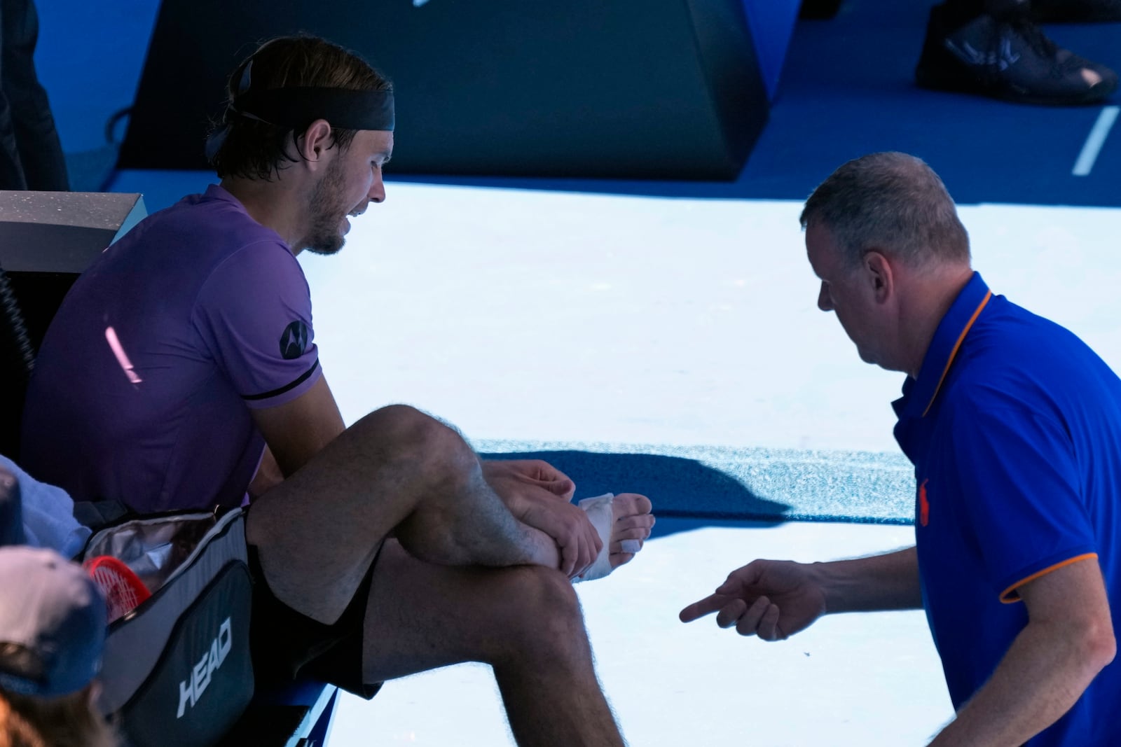 Taylor Fritz of the U.S. receives treatment from a trainer during his third round match against Gael Monfils of France at the Australian Open tennis championship in Melbourne, Australia, Saturday, Jan. 18, 2025. (AP Photo/Manish Swarup)