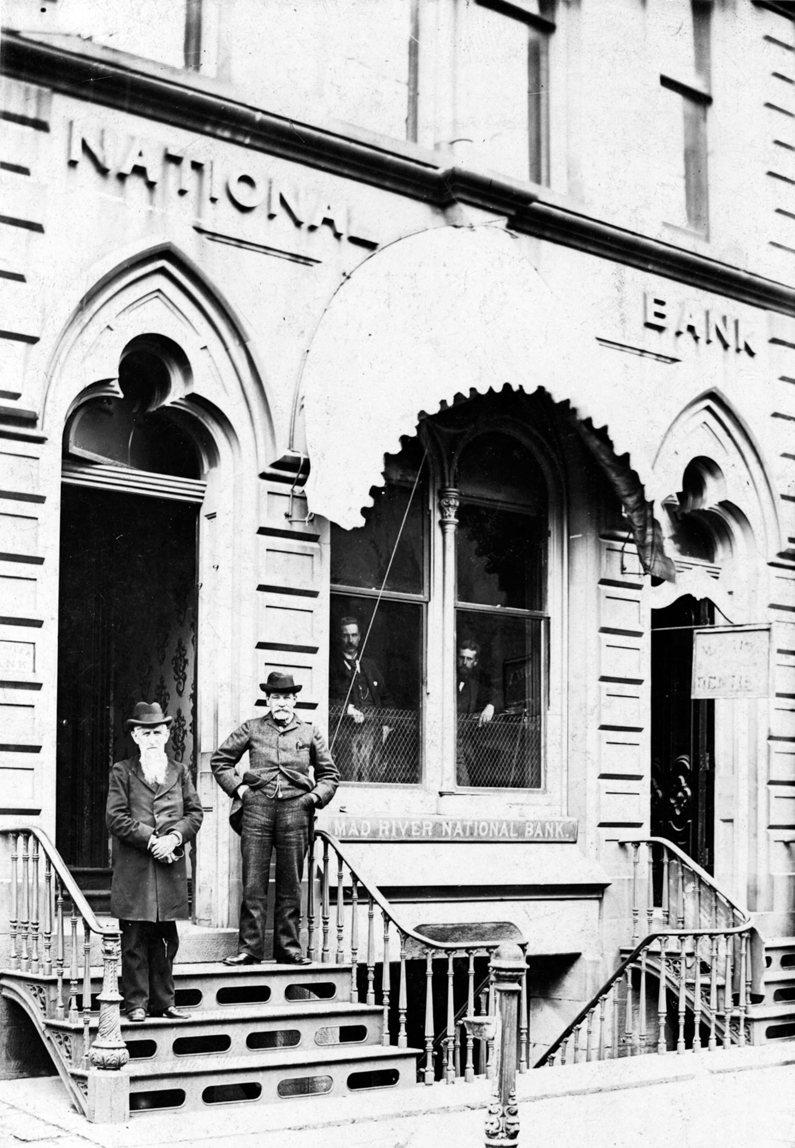 In 1846 that Mad River Valley Bank of Ohio opened as the first bank in Springfield with a capital of $100,000. It was incorporated as the Mad River National Bank in January 1865 and in 1869, the building shown here at 22 E. Main Street was constructed. Employees of the bank are shown here in the last 1870s: Thomas McGrew (left) and Charles Bacon (later president and vice president) with C.F. Harrison and Joe Sharp looking out of the windows. The Mad River Bank merged with the First National Bank of Springfield in 1928 and moved to what is today known as Hull Plaza at the northwest corner of Main and Fountain. PHOTO COURTESY OF THE CLARK COUNTY HISTORICAL SOCIETY