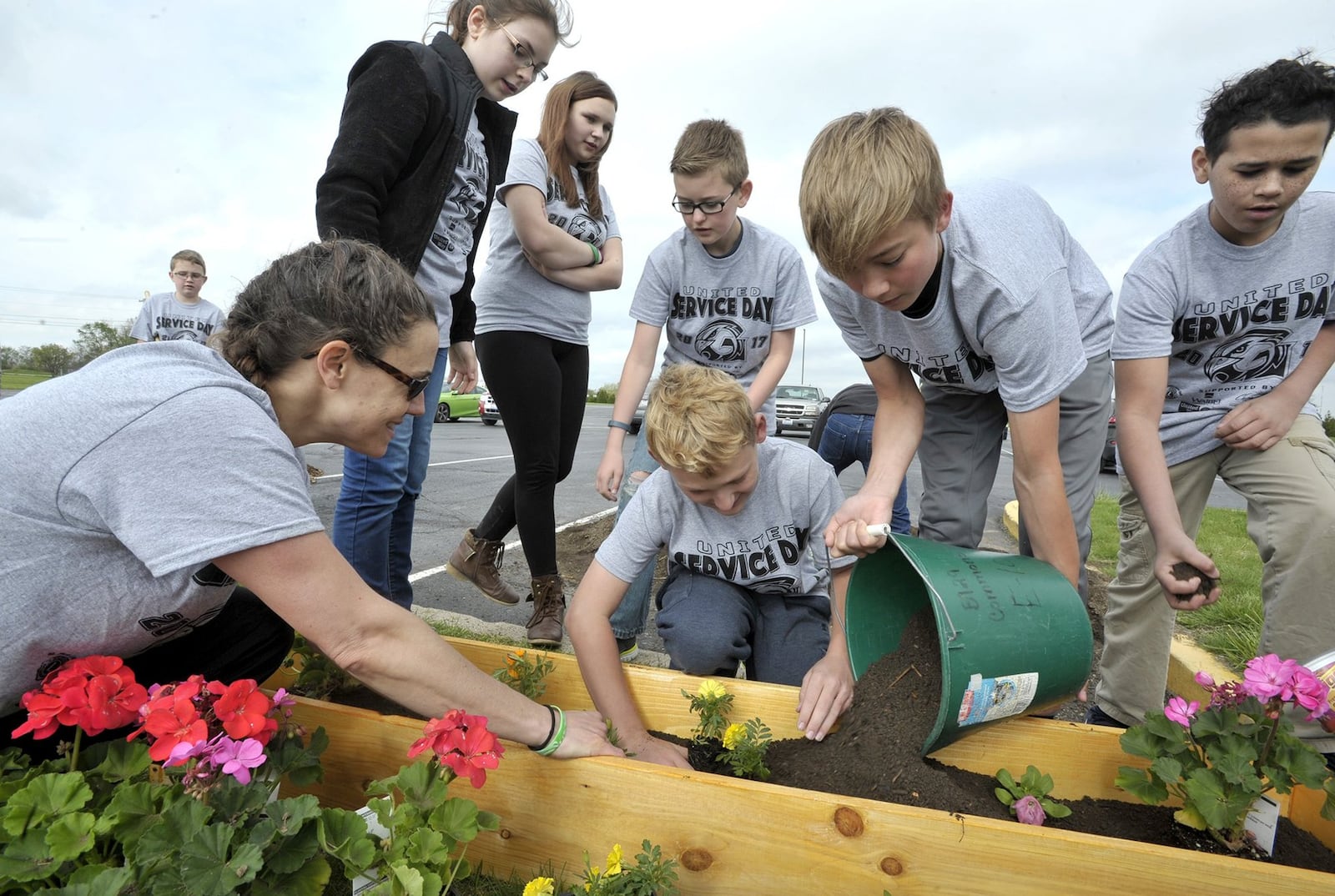 Jennifer Boggs, a teacher at Graham Middle School, leads a group of students as they plant flowers in new flower boxes for Service Day Friday.