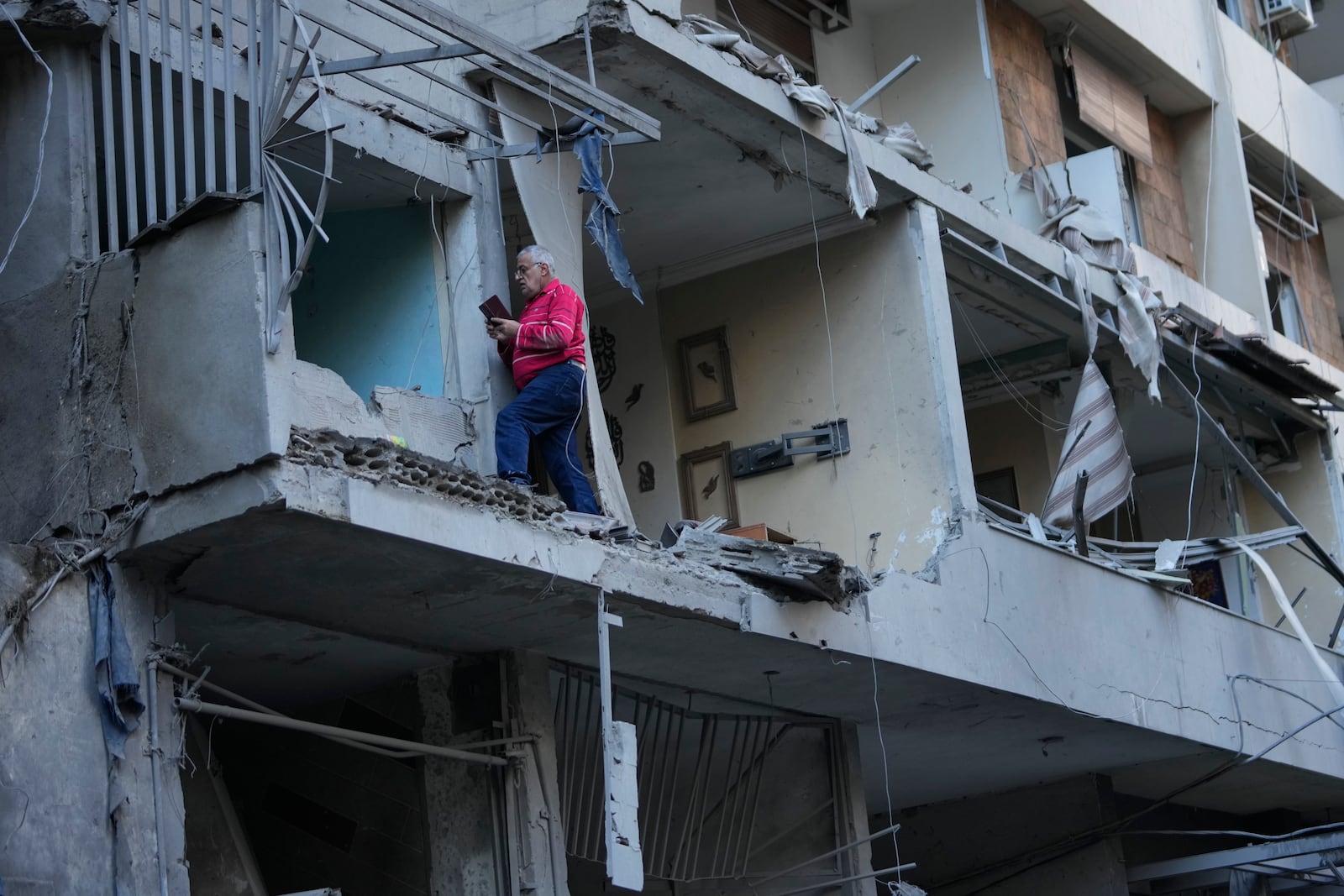 A man takes pictures by his mobile phone at his damaged apartment which was resulted from Sunday's Israeli airstrike in Dahiyeh, in the southern suburb of Beirut, Lebanon, Monday, Nov. 25, 2024. (AP Photo/Hussein Malla)