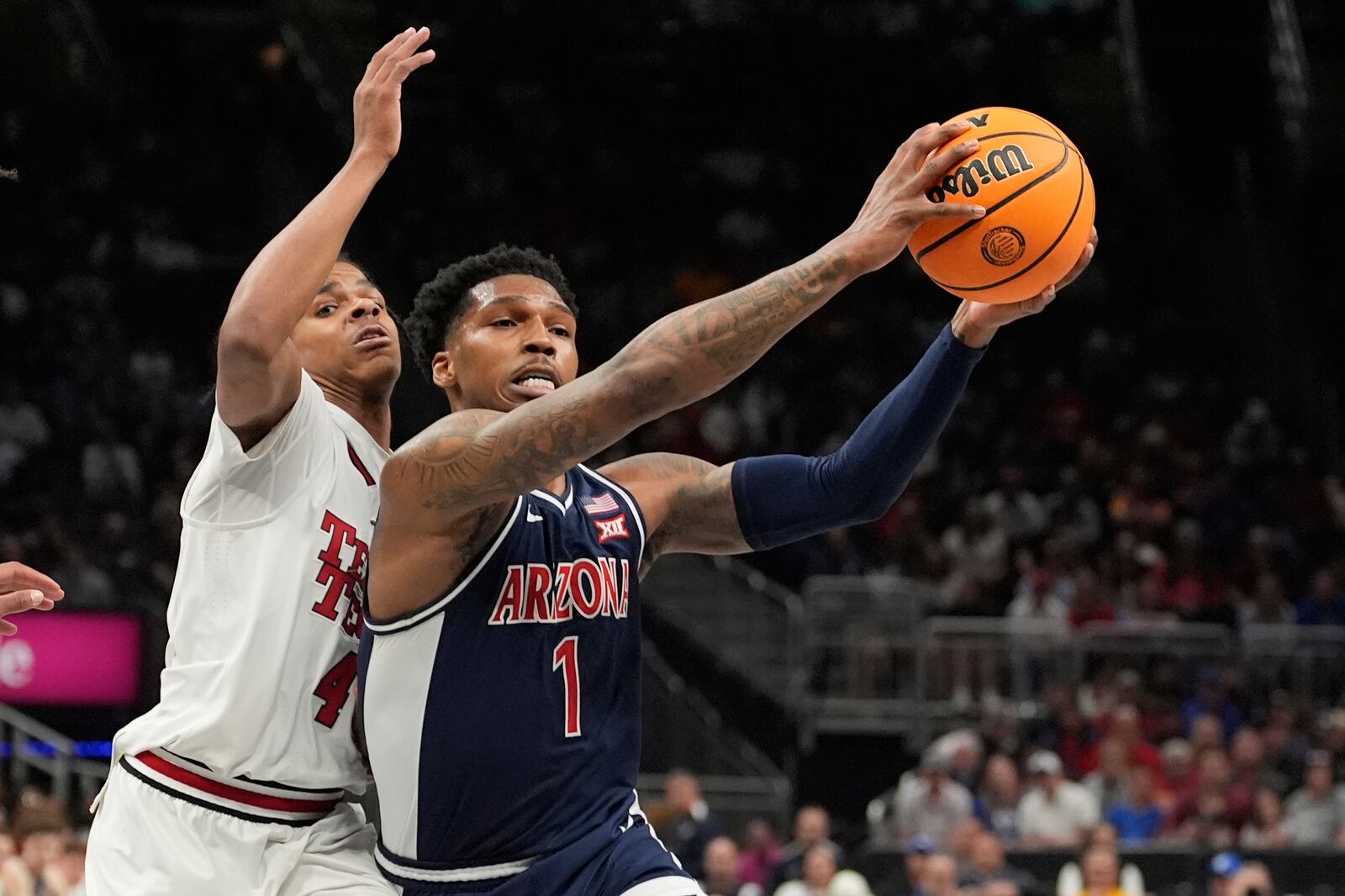 Arizona's Caleb Love (1) heads to the basket past Texas Tech's Christian Anderson (4) during the first half of an NCAA college basketball game in the semifinal round of the Big 12 Conference tournament, Friday, March 14, 2025, in Kansas City, Mo. (AP Photo/Charlie Riedel)