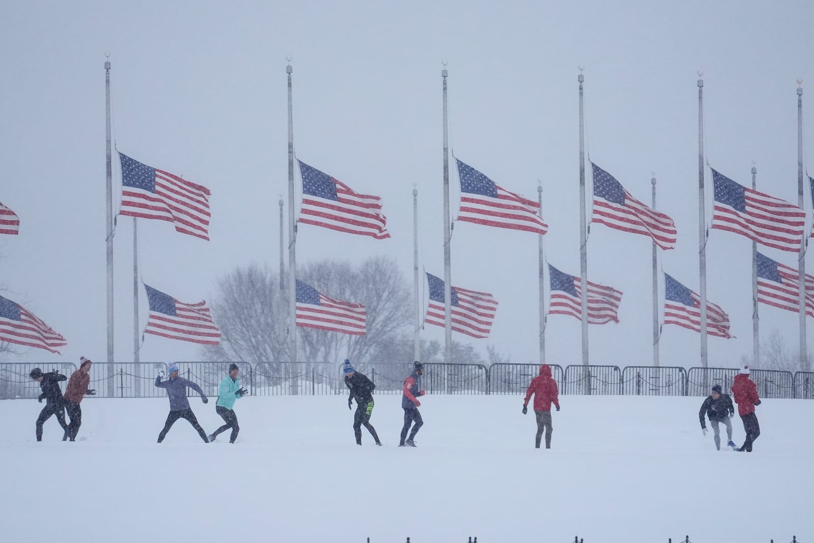 FILE - People engage in a snowball fight in Washington, Jan. 6, 2025, as U.S. flags, along the base of the Washington Monument, fly at half-staff in honor of former President Jimmy Carter, who died on Dec. 29 at the age of 100. (AP Photo/Matt Rourke, File)