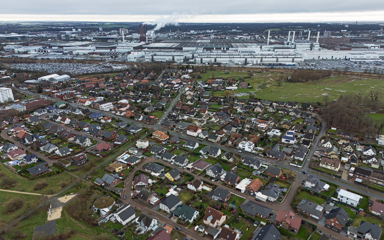 FILE - The Volkswagen main plant is seen behind single-family houses during a strike of VW employees of Germany's largest carmaker in Wolfsburg, Germany, Monday, Dec. 9, 2024. (AP Photo/Martin Meissner, File)