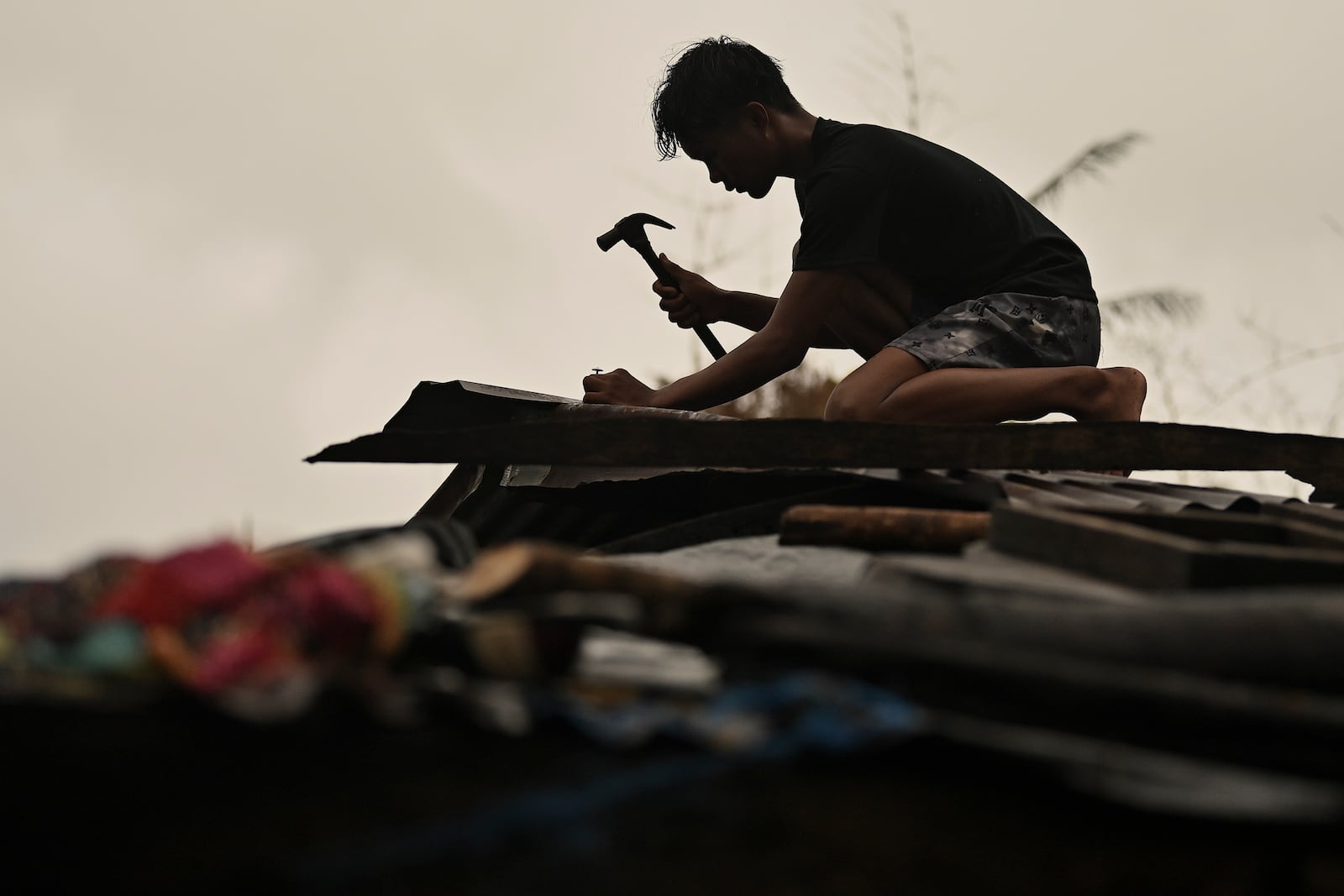 A resident reinforces his roof in Santa Ana, Cagayan Province, northern Philippines as they anticipate Typhoon Usagi to hit their area Thursday, Nov. 14, 2024. (AP Photo/Noel Celis)