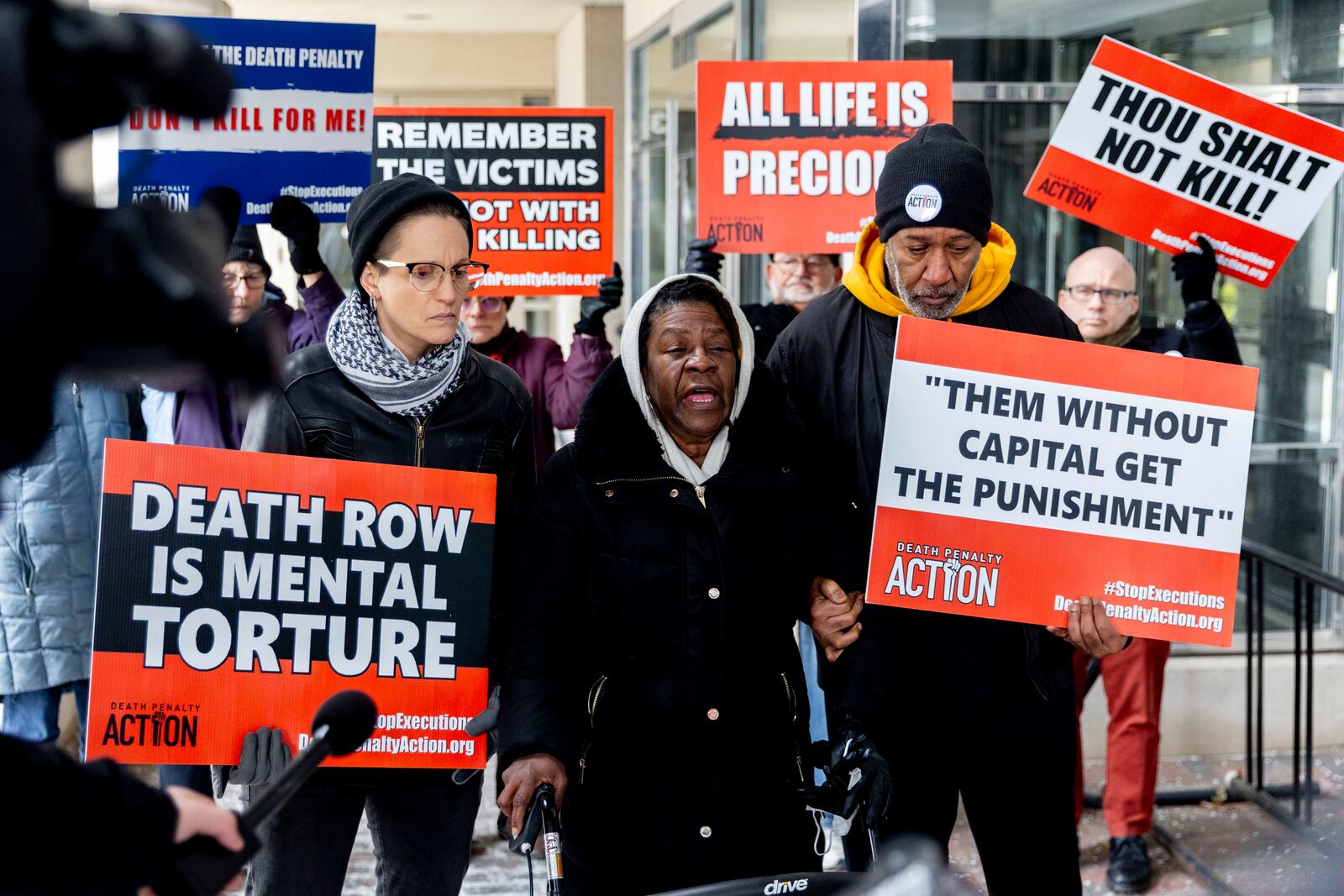 Lizz Schallert, left, and Charles Keith, right, stand in solidarity with Carol Frazier, mother of Demetrius Frazier, as she pleads publicly Tuesday, Jan. 28, 2025, in Lansing, Mich., to Gov. Gretchen Whitmer to bring home her son Demetrius, a Detroit man convicted of rape and a separate murder of a 14-year-old in the early 1990s, who was serving a life sentence when he was charged with another murder in Alabama and is scheduled to be executed there Feb. 6. (Jake May/MLive.com/The Flint Journal via AP)